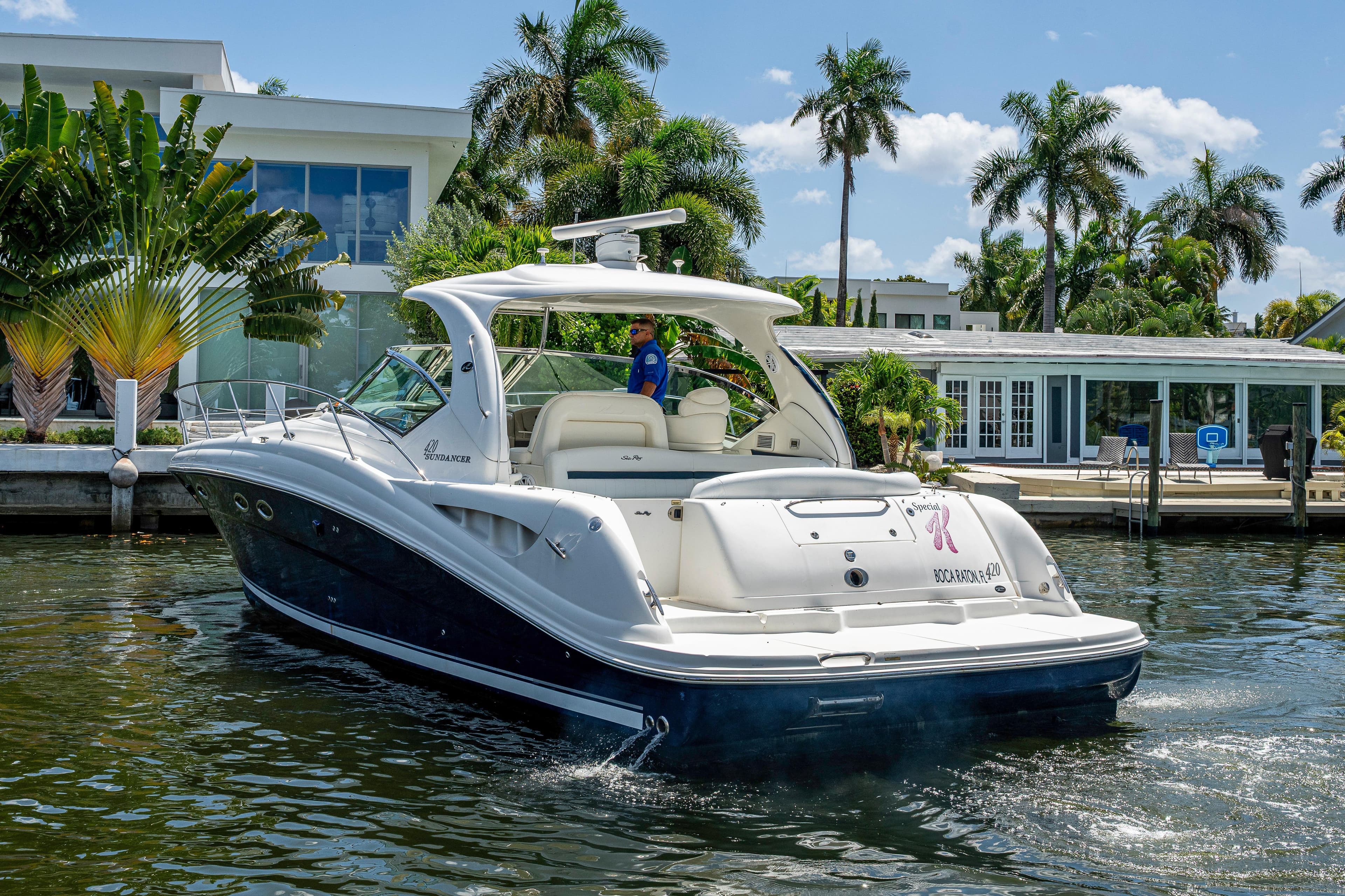 2005 Sea Ray 420 Sundancer yacht cruising near waterfront homes with palm trees.