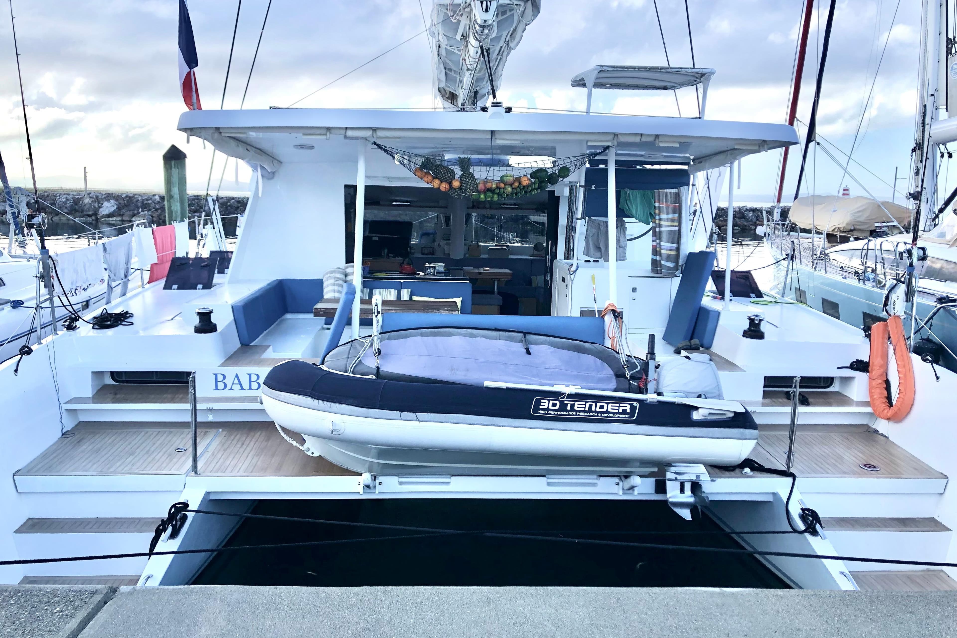 2018 Swiss Cat Yachts 48 with tender docked at marina, featuring spacious deck area.