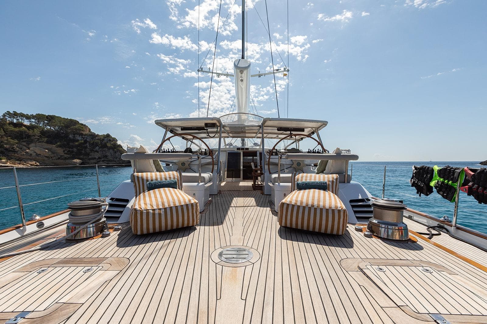 Luxurious 1999 Camper & Nicholsons Cutter yacht deck with striped loungers and ocean view.
