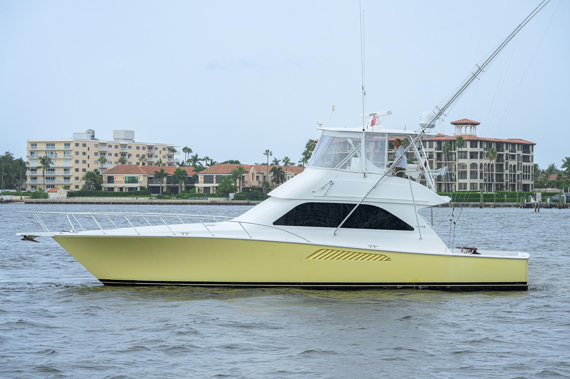 2004 Viking 48 Convertible yacht cruising near waterfront buildings.