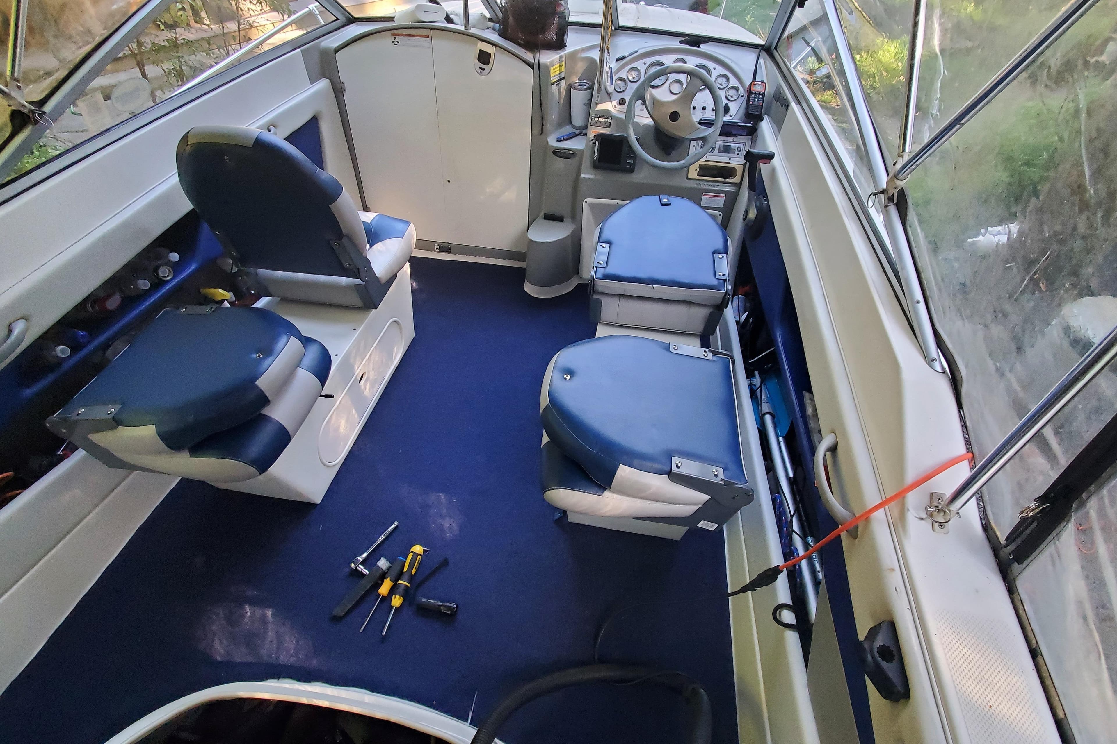 Interior of a 2006 Bayliner 192 Discovery Cuddy boat with blue seating and tools.