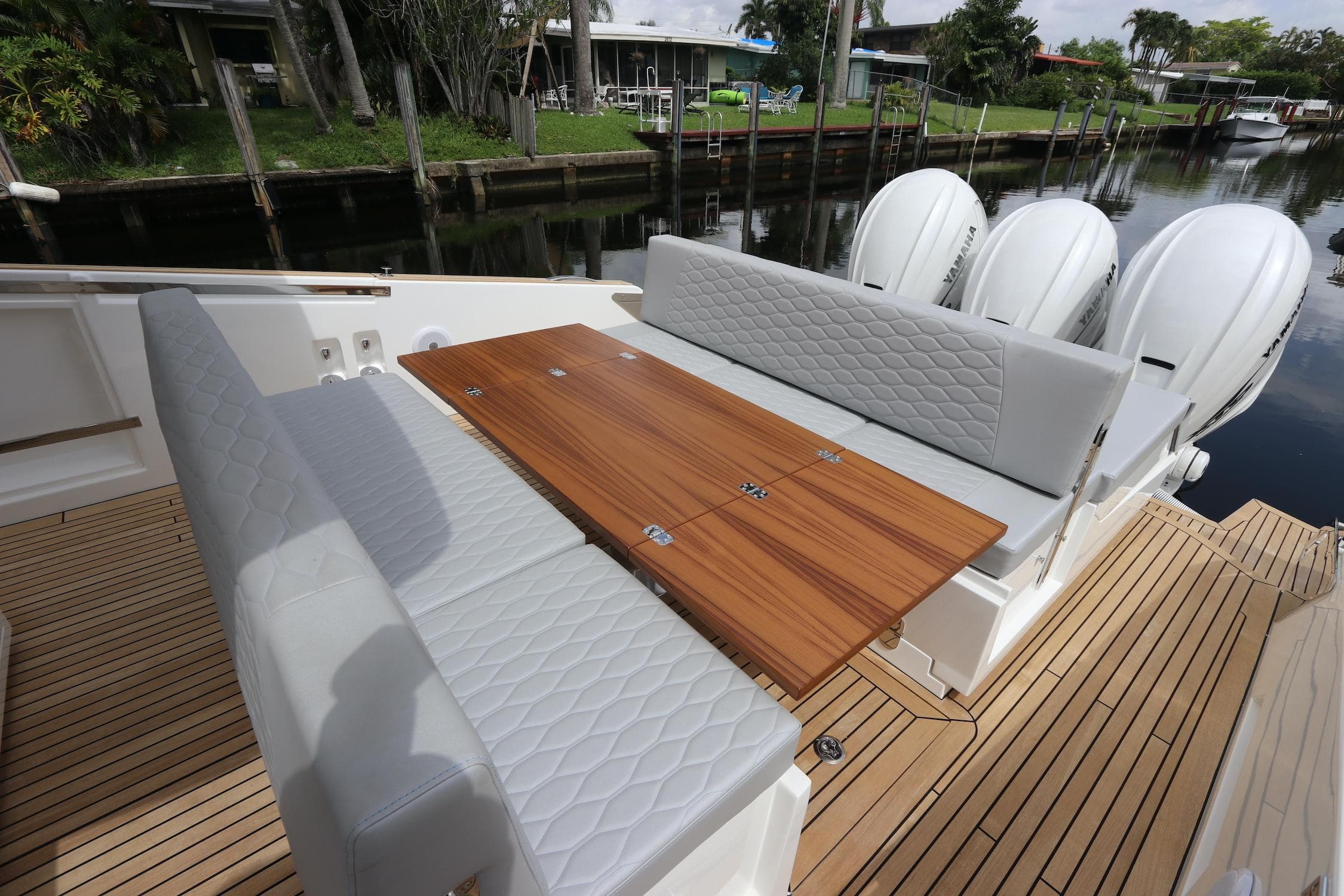 2024 Astondoa 377 Coupe Outboard with elegant seating and wooden table on deck.