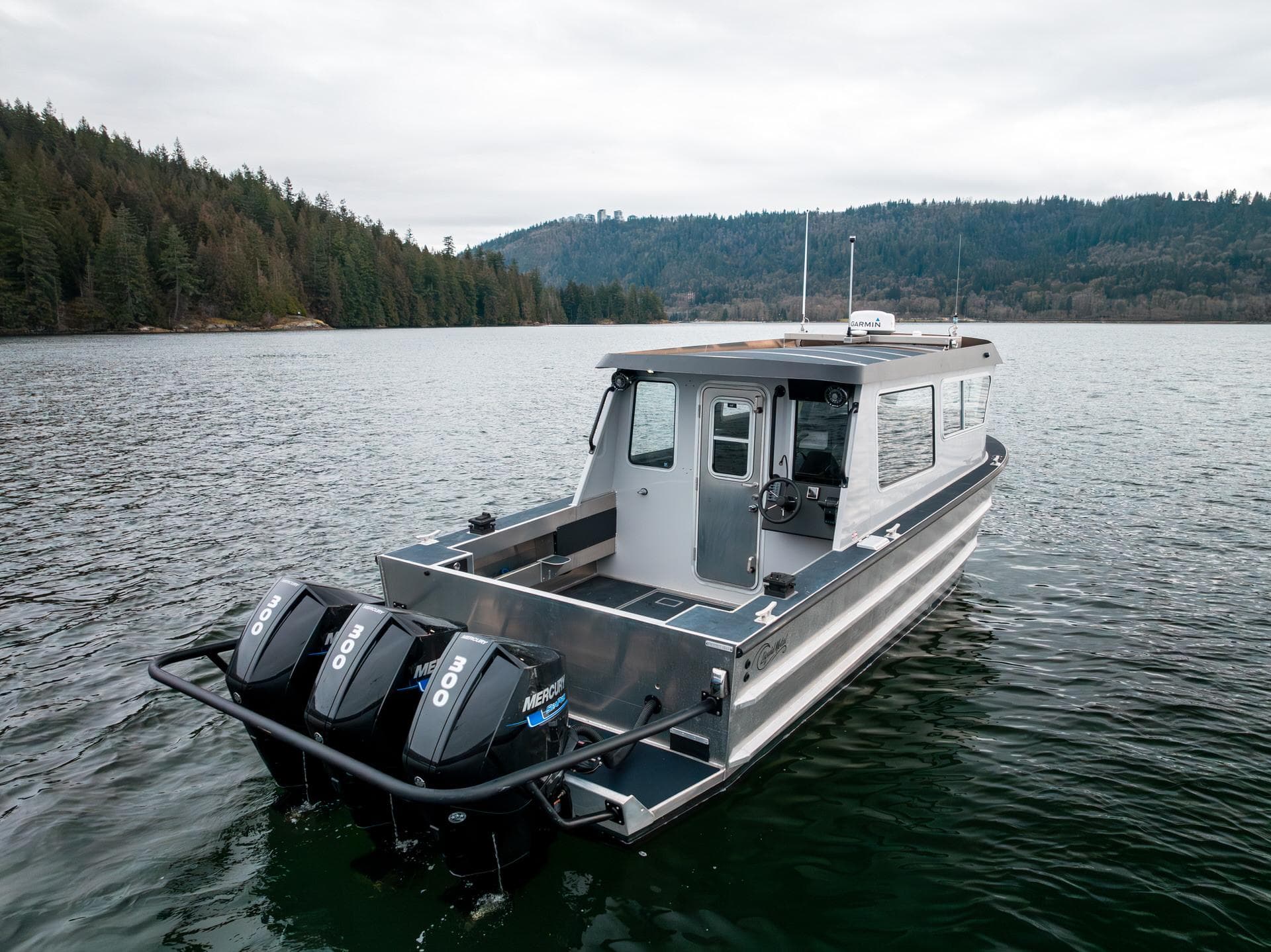 2023 Liquid Metal Marine Maquinna Crew boat on a serene lake with forested shoreline.