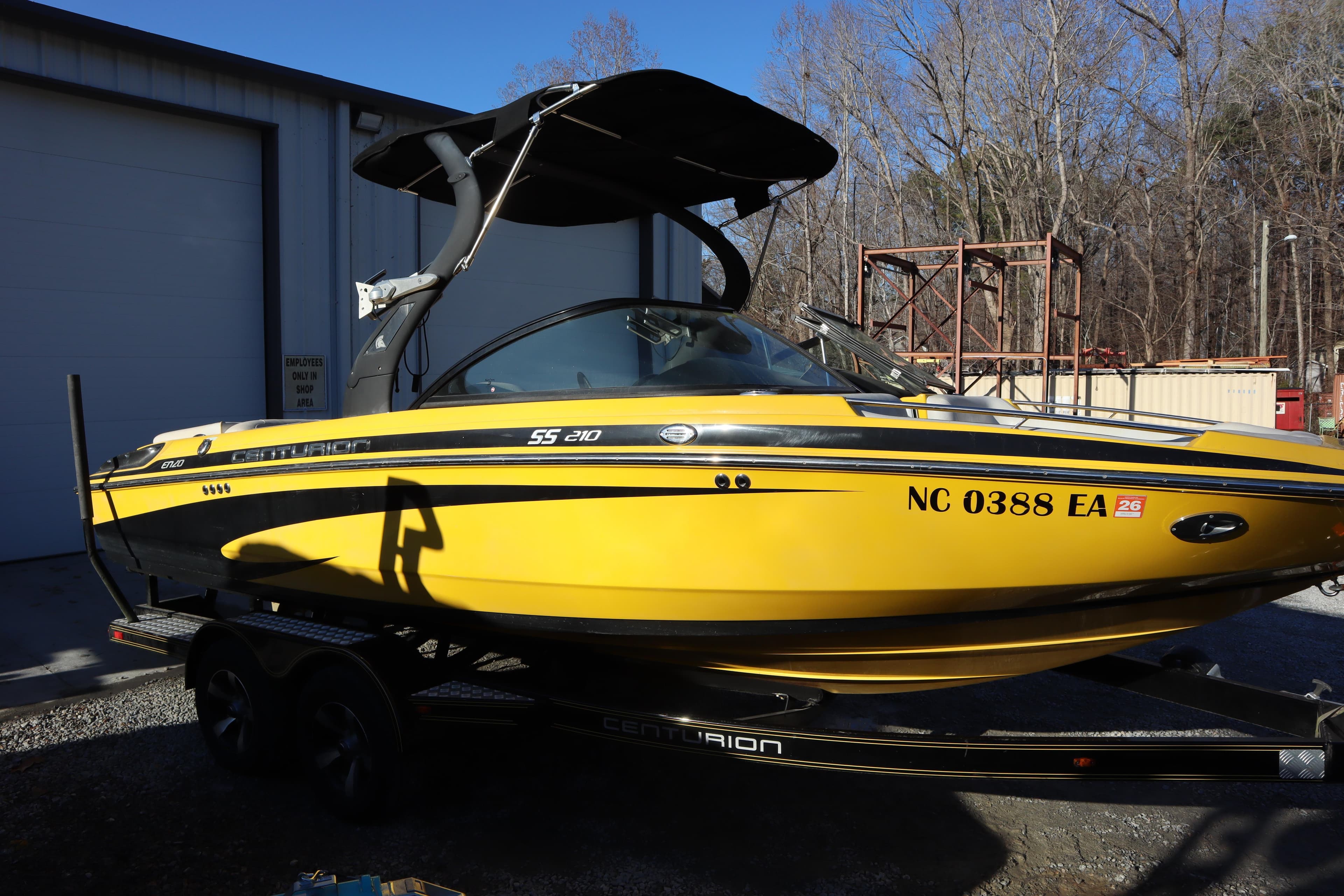 2014 Centurion Enzo SS210 yellow boat on trailer, parked outside a building.