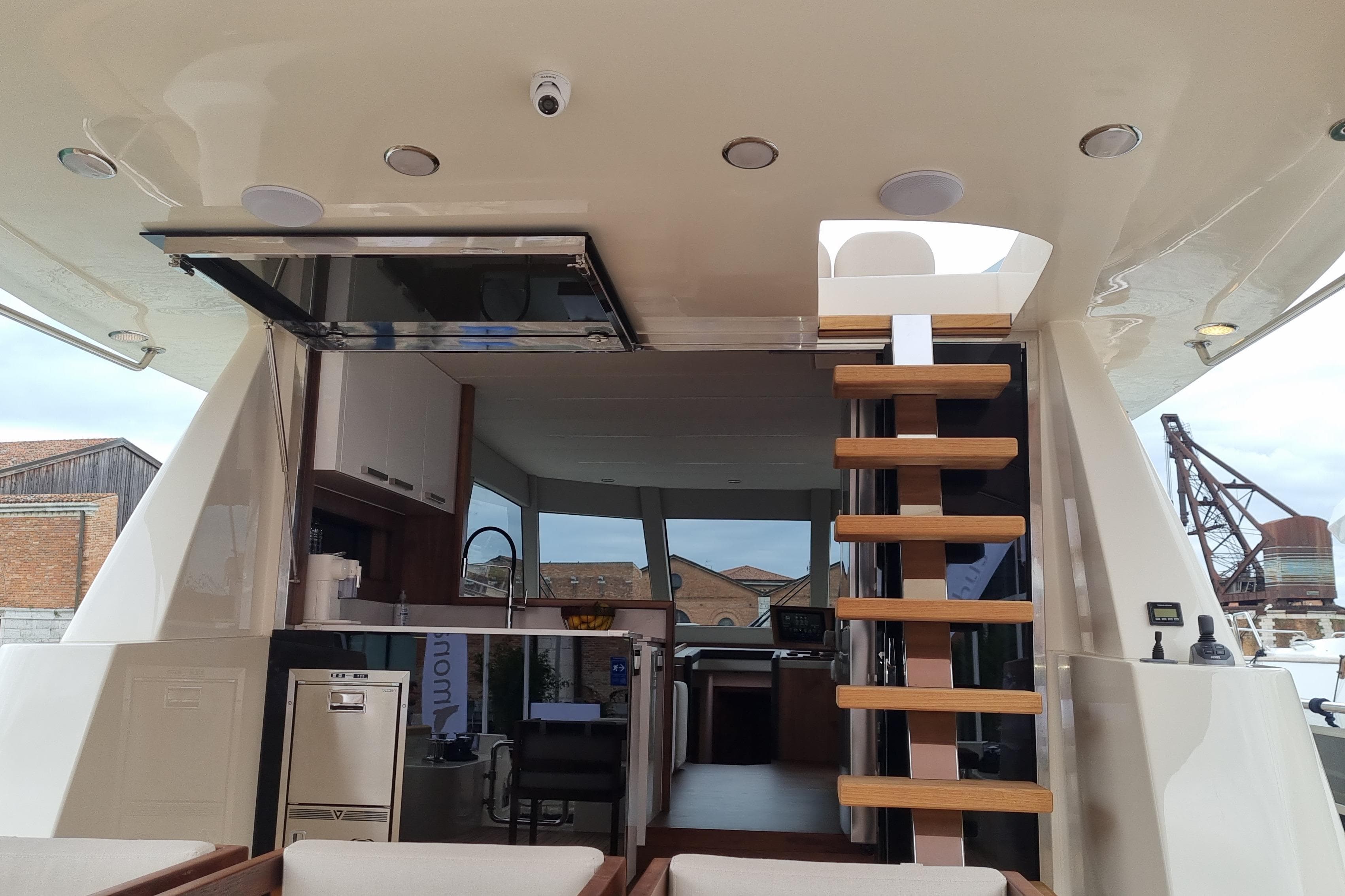 Interior view of 2026 Monachus 70 Fly yacht with modern kitchen and wooden staircase.