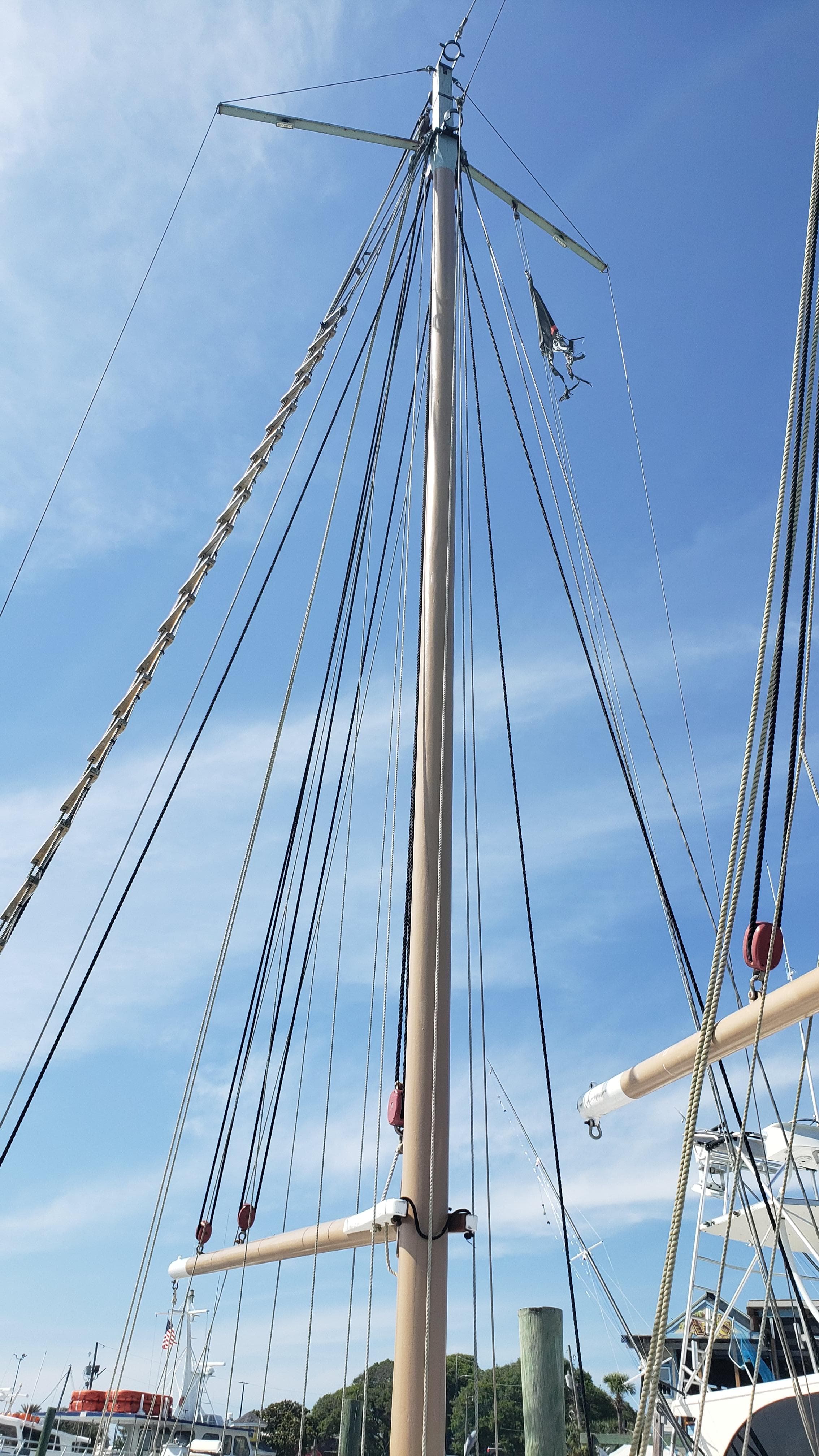 Tall mast of a 1996 Custom Biloxi Schooner against a clear blue sky.