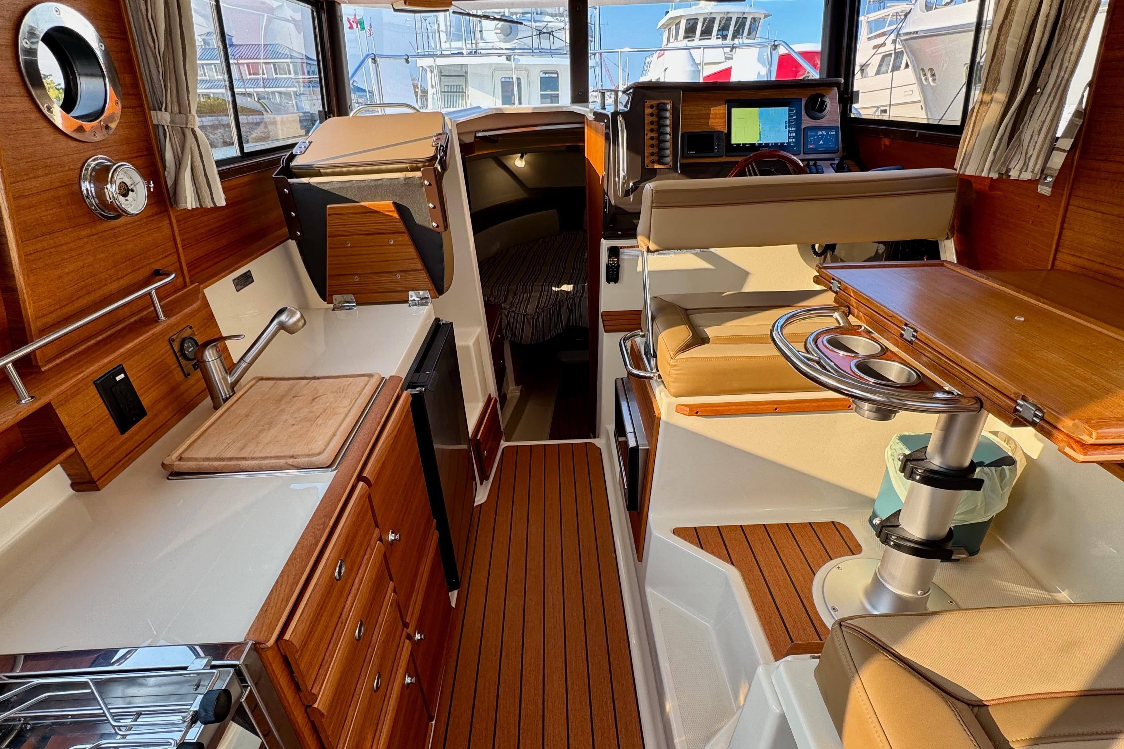 2024 Ranger Tugs R-27 interior with wood finish, kitchenette, and seating area.