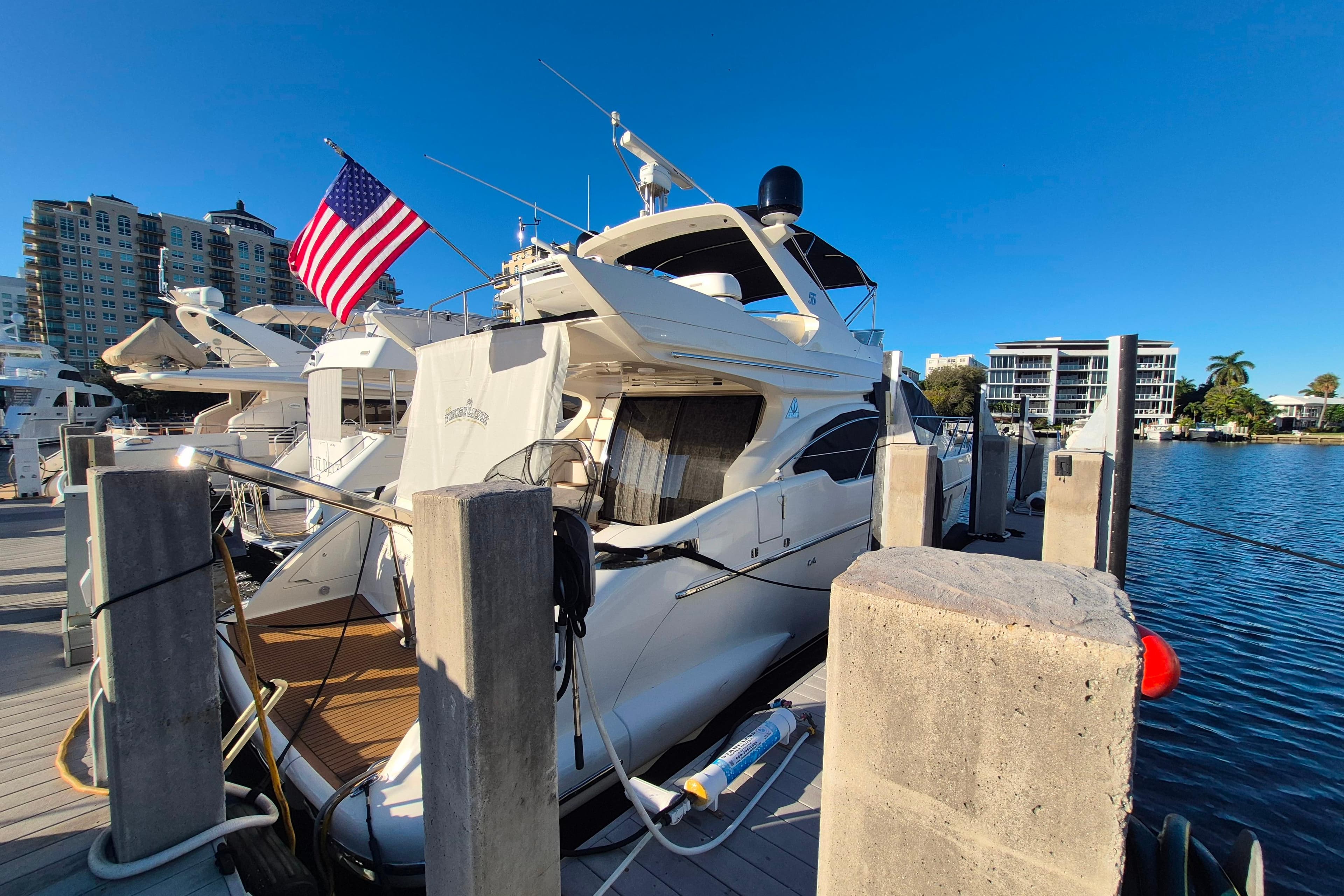 Luxury 2004 Azimut 55E yacht docked at marina with American flag.