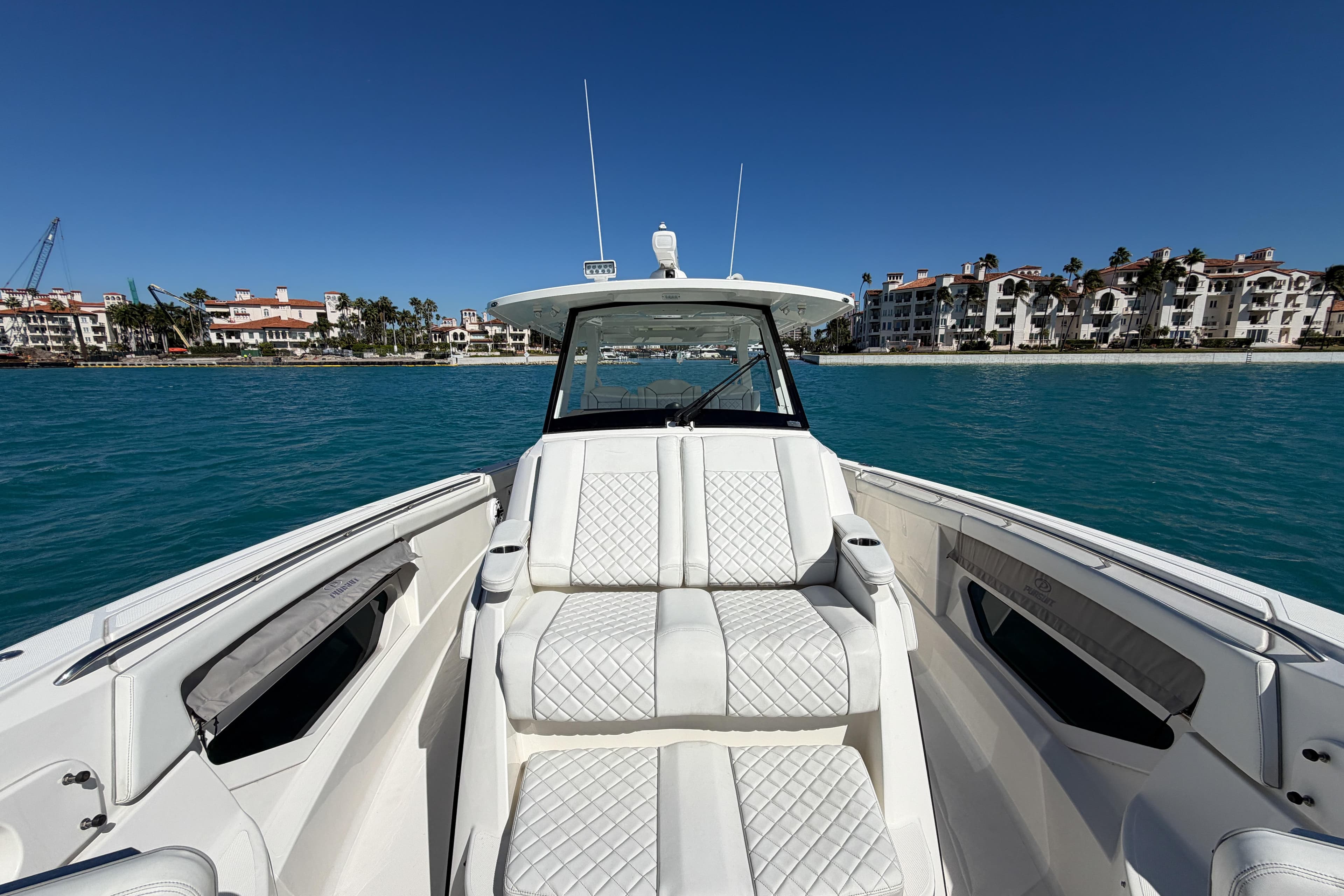 2021 Pursuit S 378 Sport boat with luxurious seating, cruising near waterfront buildings.