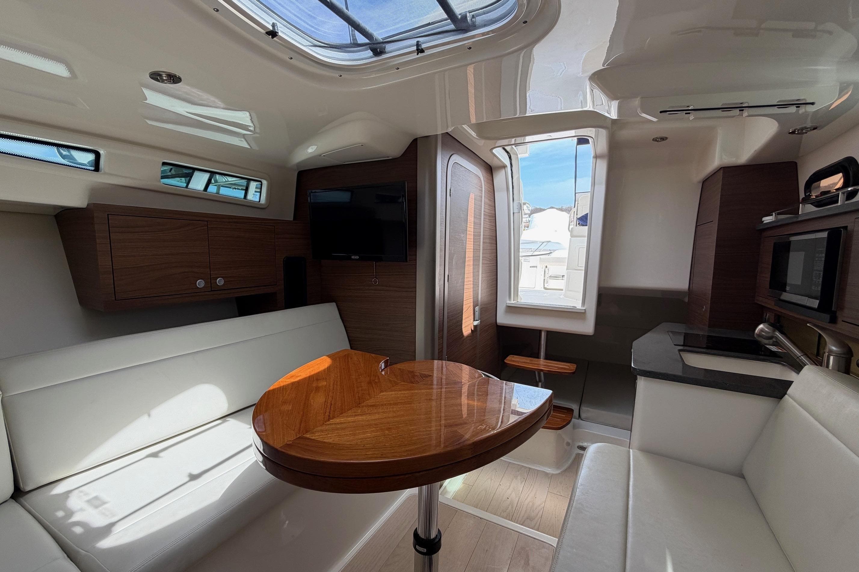 Interior of 2023 Boston Whaler 325 Conquest, featuring modern seating, table, and kitchenette.