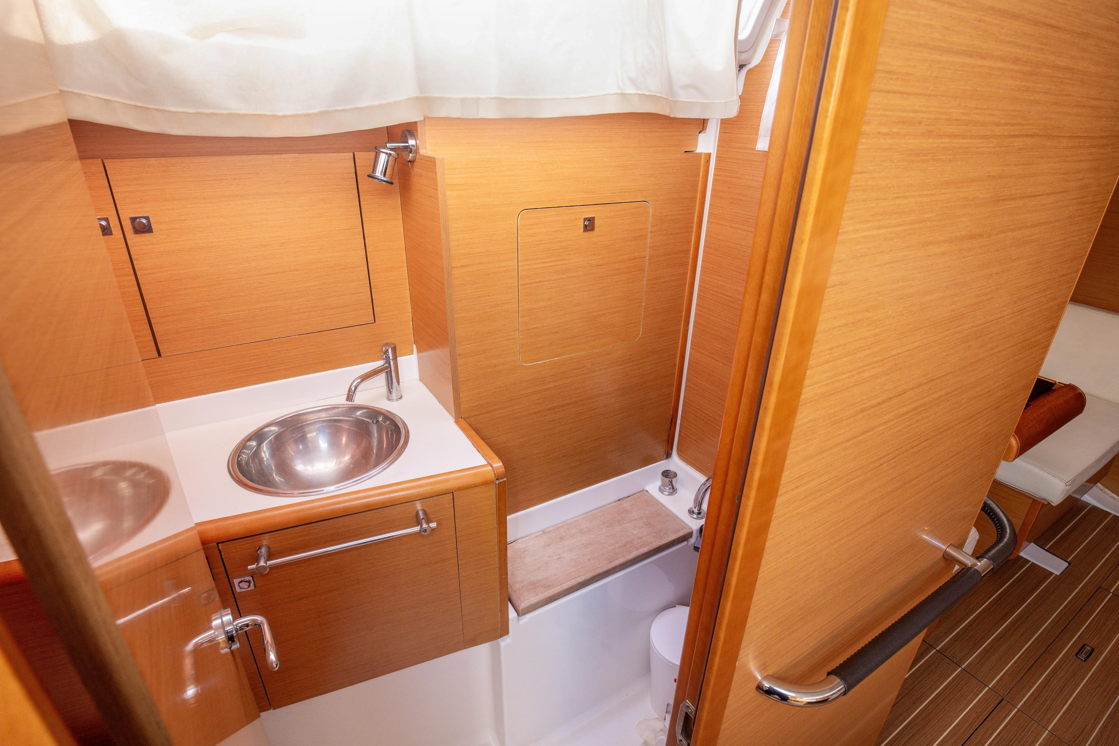 2013 Jeanneau Sun Odyssey 439 bathroom with wooden cabinetry and stainless steel sink.
