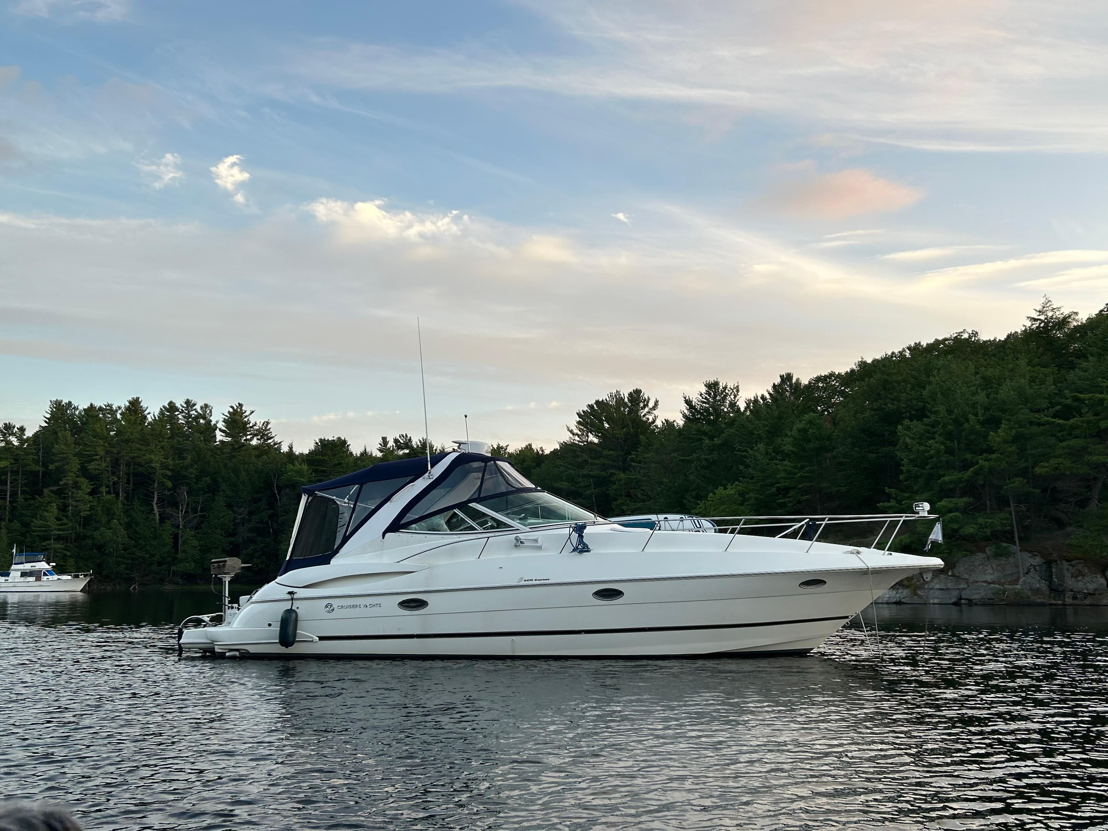 2003 Cruisers Yachts 3470 Express on a tranquil lake at sunset.