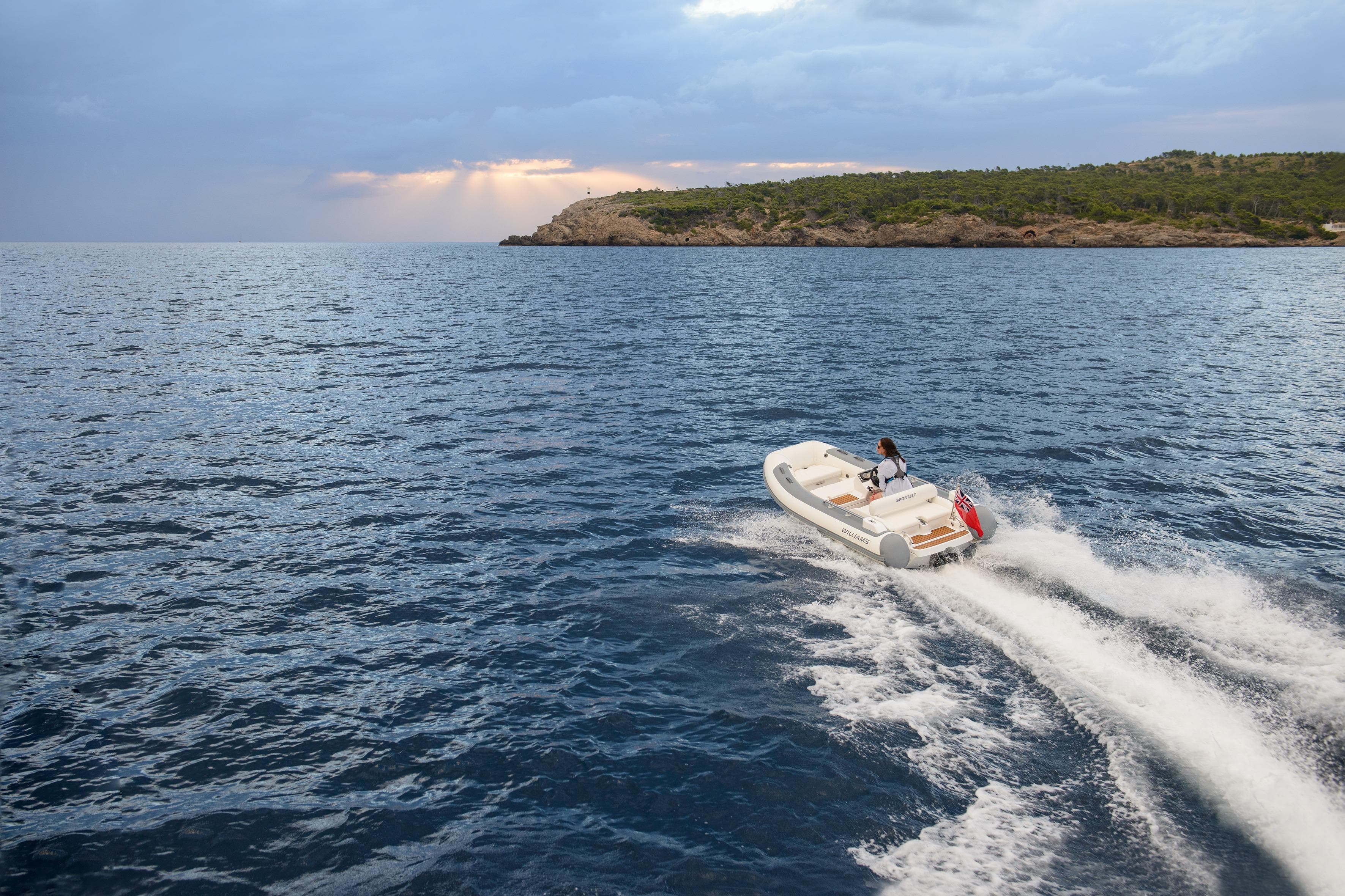 2026 Williams Jet Tenders Sportjet 395 cruising on open water near a scenic coastline.
