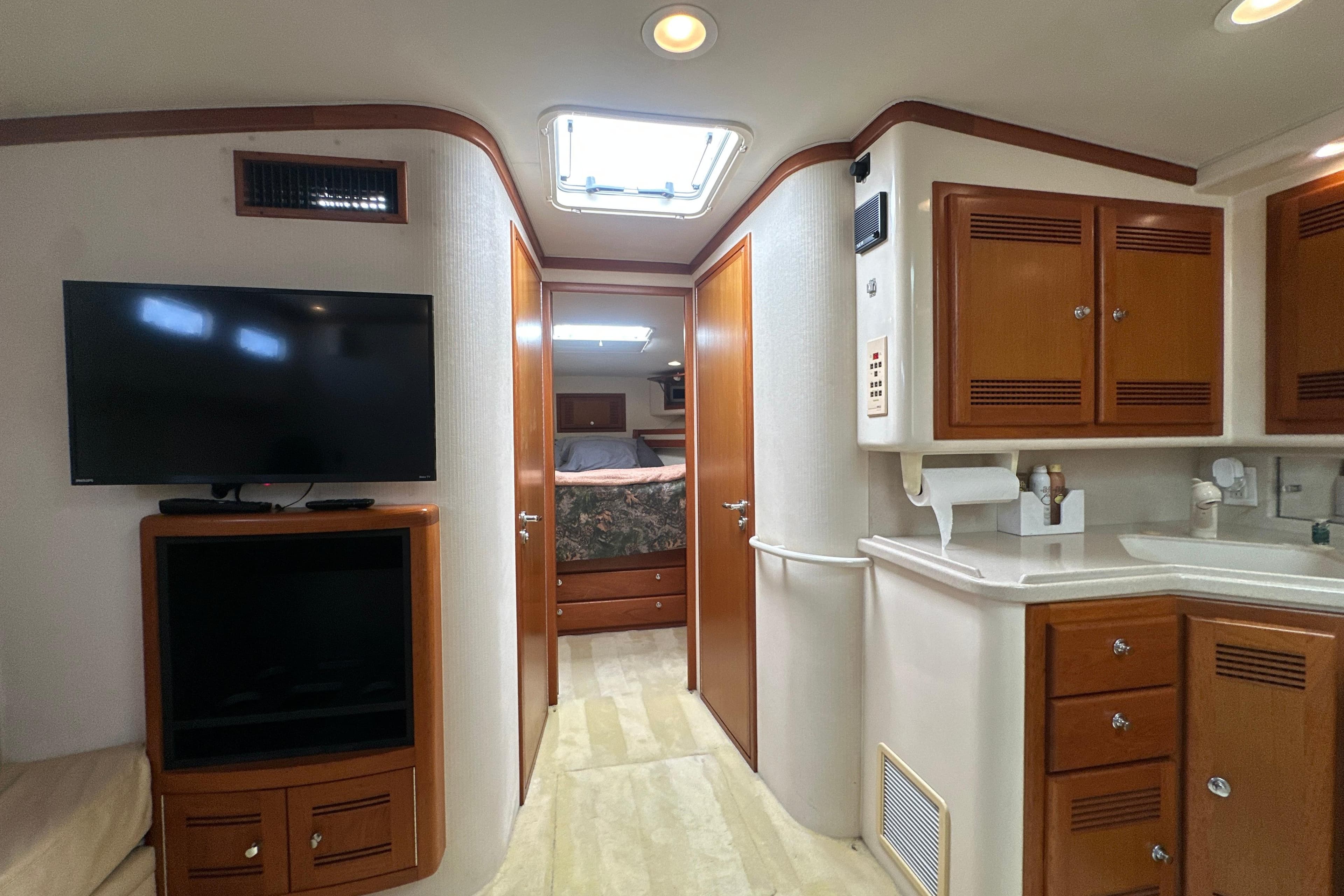 Interior of 2000 Cabo 45 Express yacht with TV, cabinets, and bedroom view.