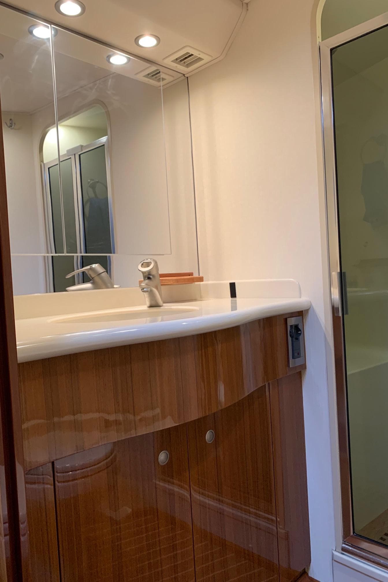 Bathroom interior of a 2007 Viking 52 yacht with wooden cabinetry and glass shower.