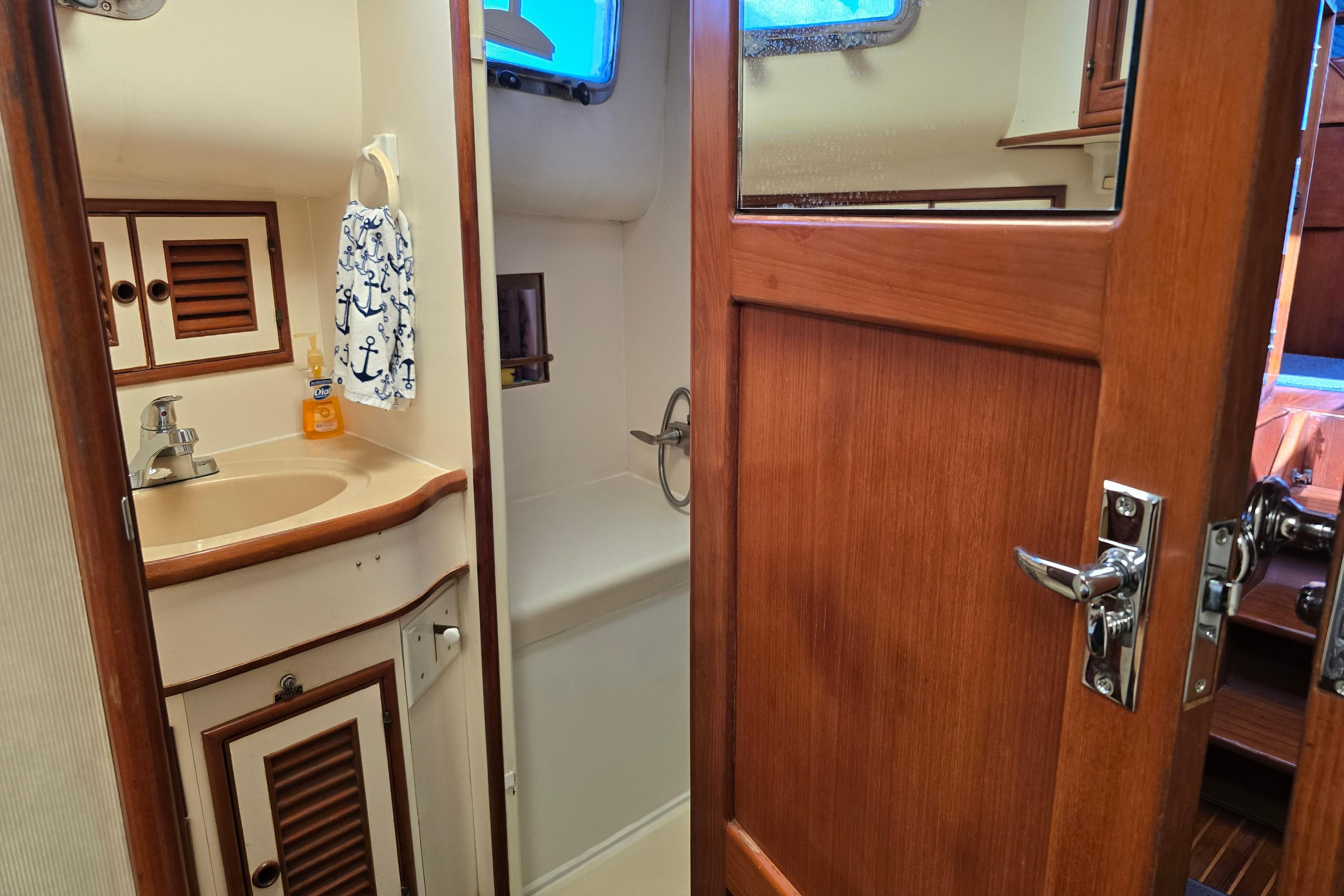 1989 Offshore Yachts 48 Sedan bathroom with wooden door, sink, and nautical decor.