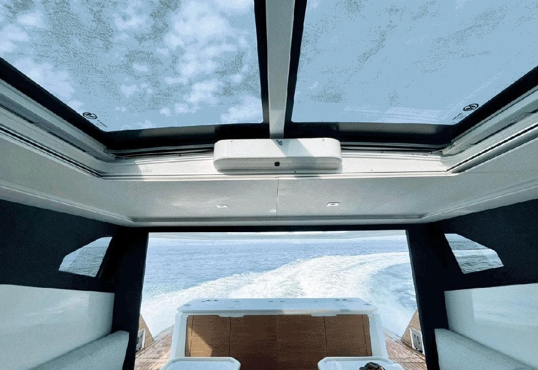 Interior view of 2025 Aventura 38 Sport Coupe with panoramic sunroof and ocean backdrop.