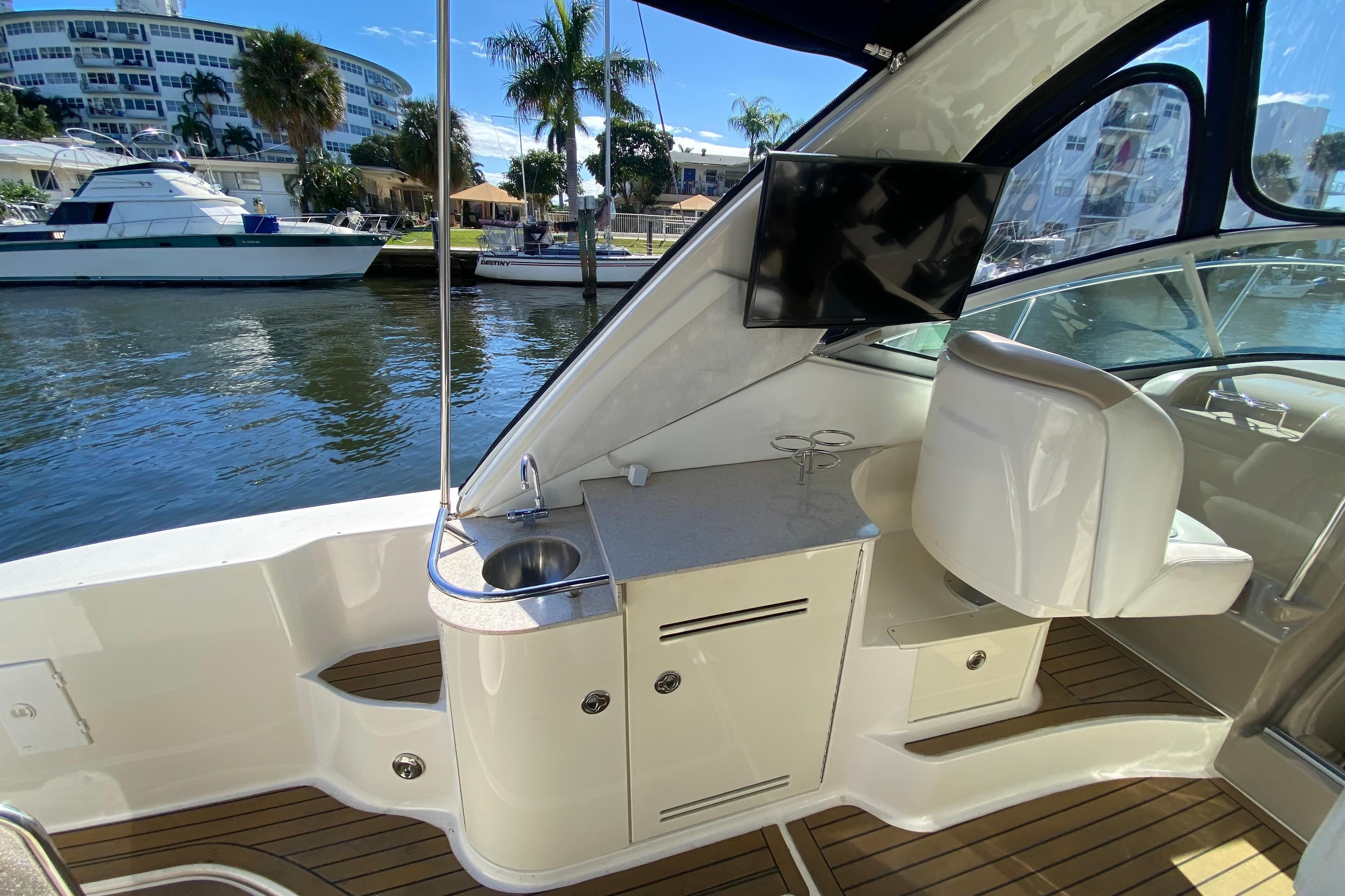 2008 Sea Ray Sundancer 330 interior with sink, TV, and seating by the water.