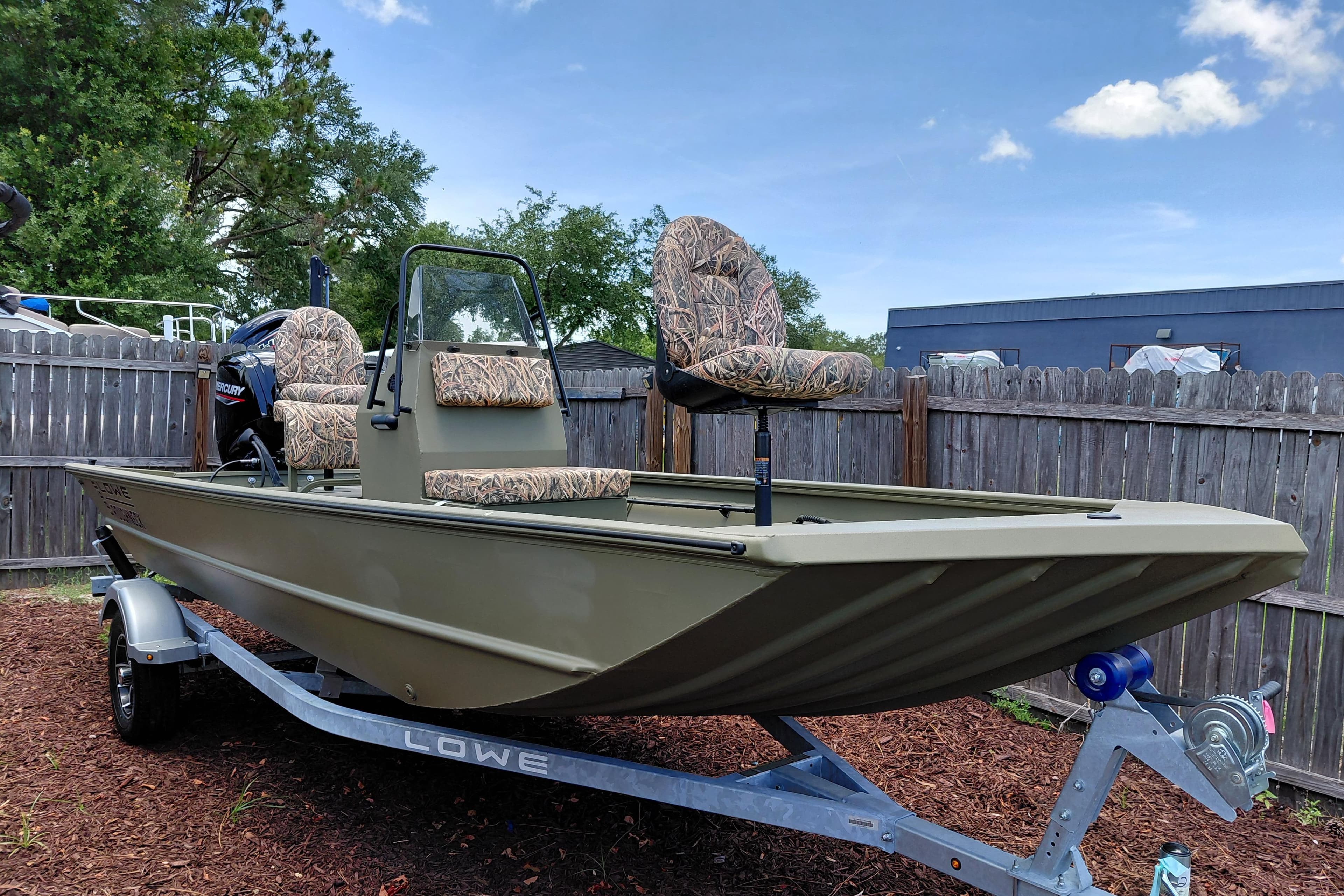 2026 Lowe Roughneck RX1860 CC boat on trailer, featuring camo seats and console.