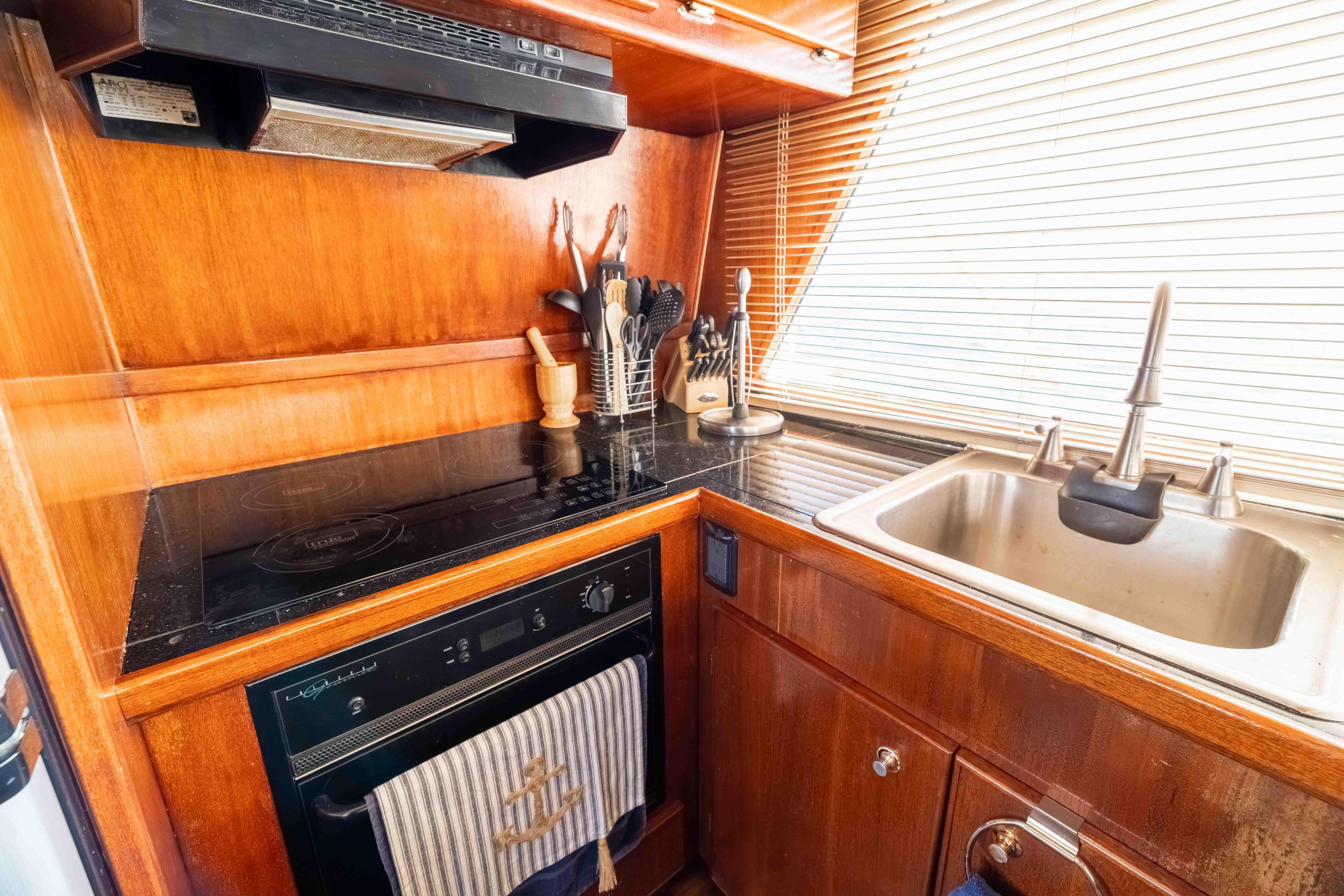 1983 Sea Ranger 45 Sundeck yacht kitchen with wooden cabinetry, stove, and sink.