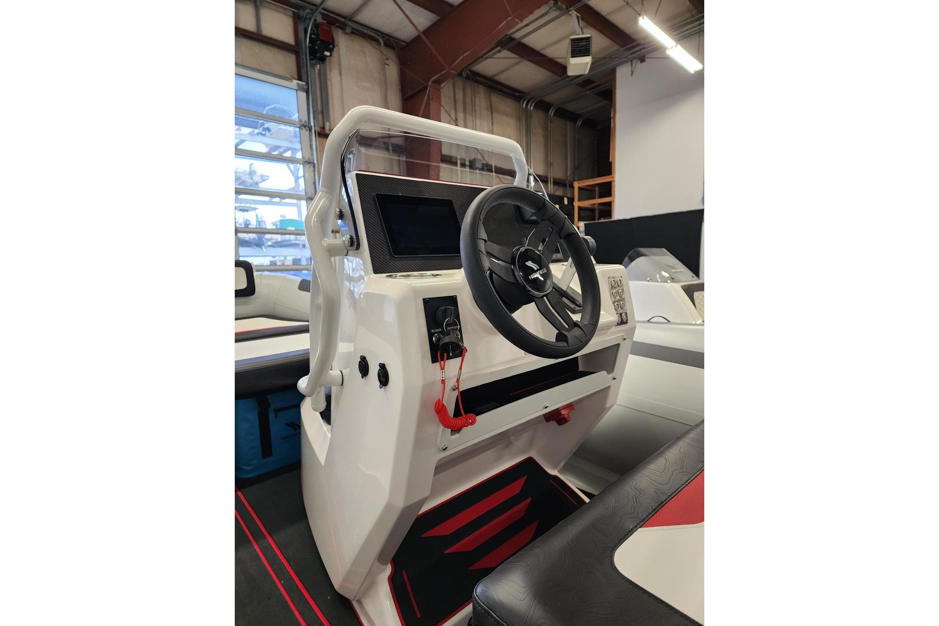 2026 Highfield Velox 560 boat console with steering wheel and control panel in a showroom.