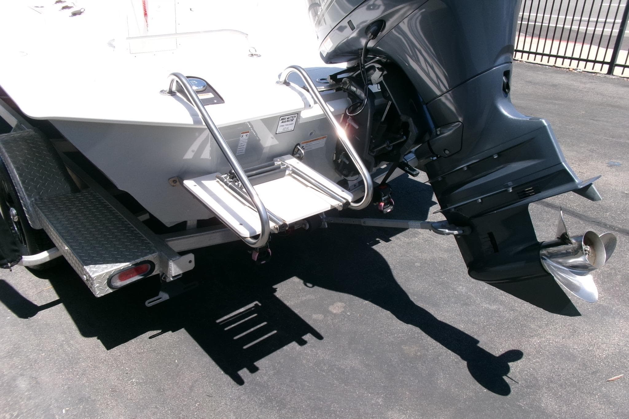 Avid 21 Fusion 2022 boat with outboard motor and swim ladder on trailer.