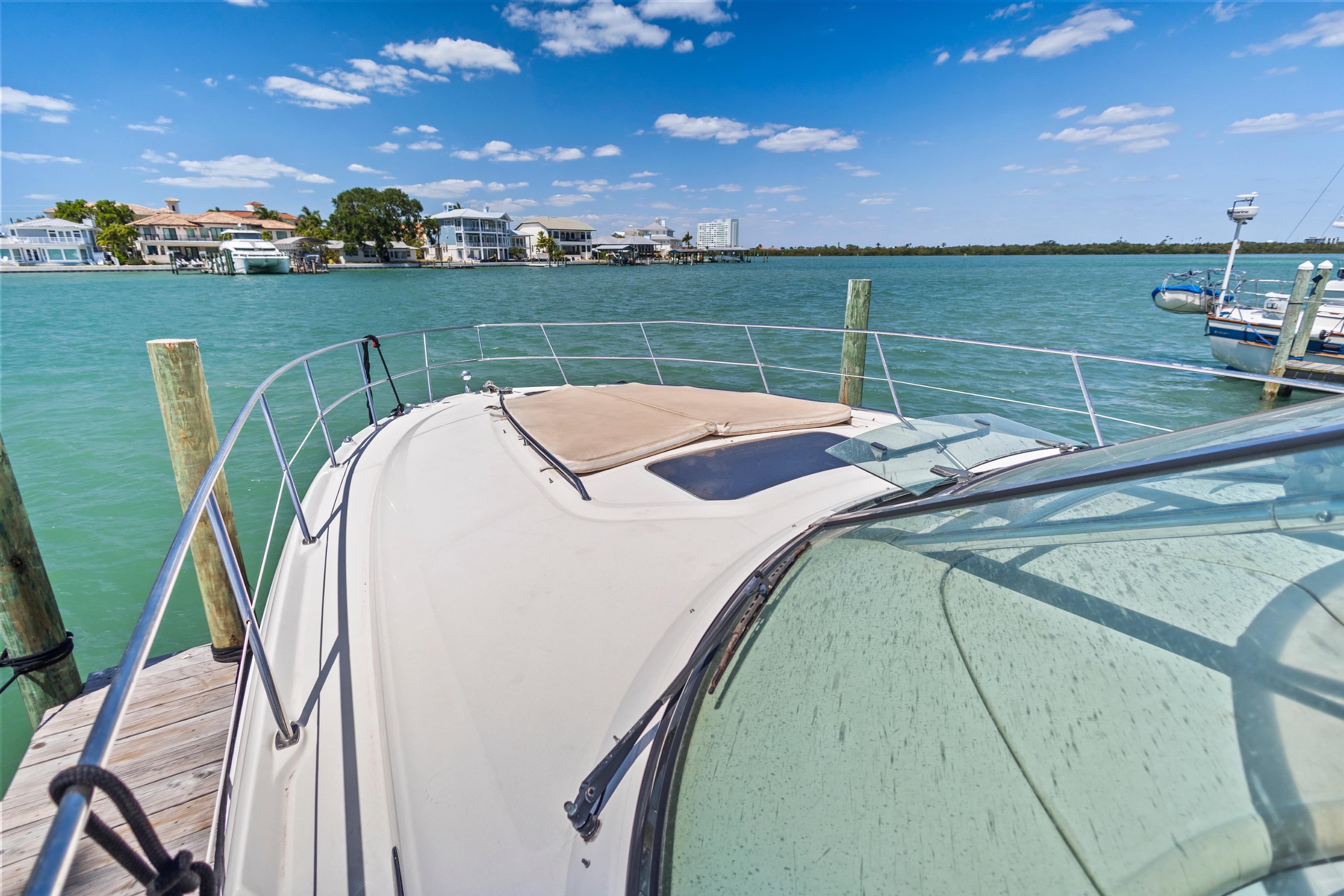 2004 Sea Ray 420 Sundancer yacht docked by waterfront homes under blue sky.