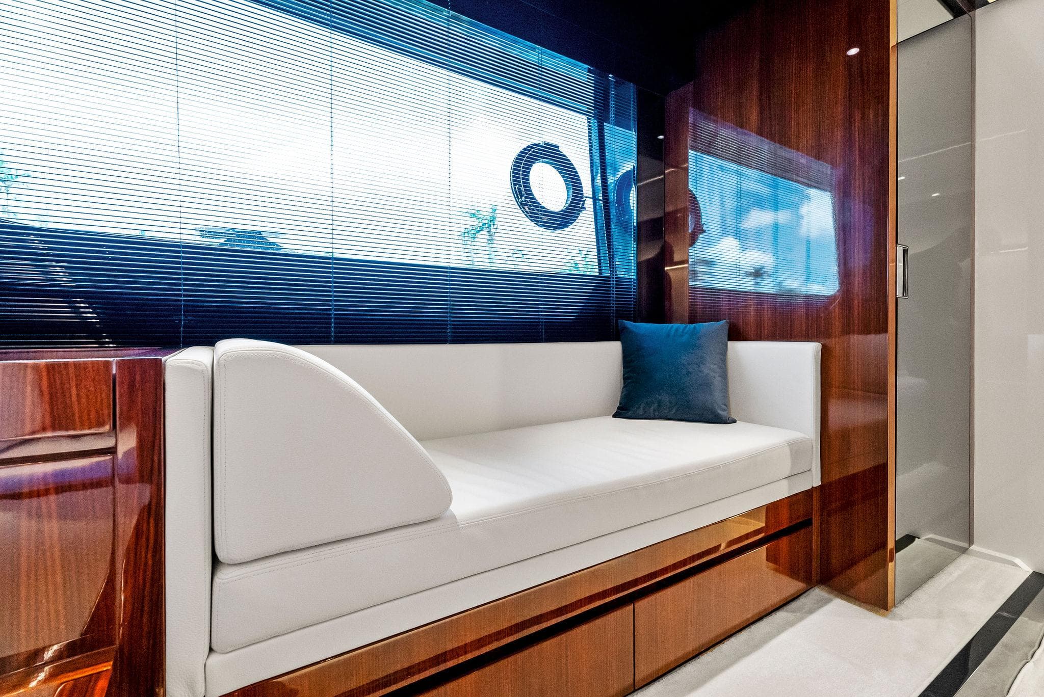 Luxurious interior of 2020 Riva 66' Ribelle yacht with white sofa and blue pillow.