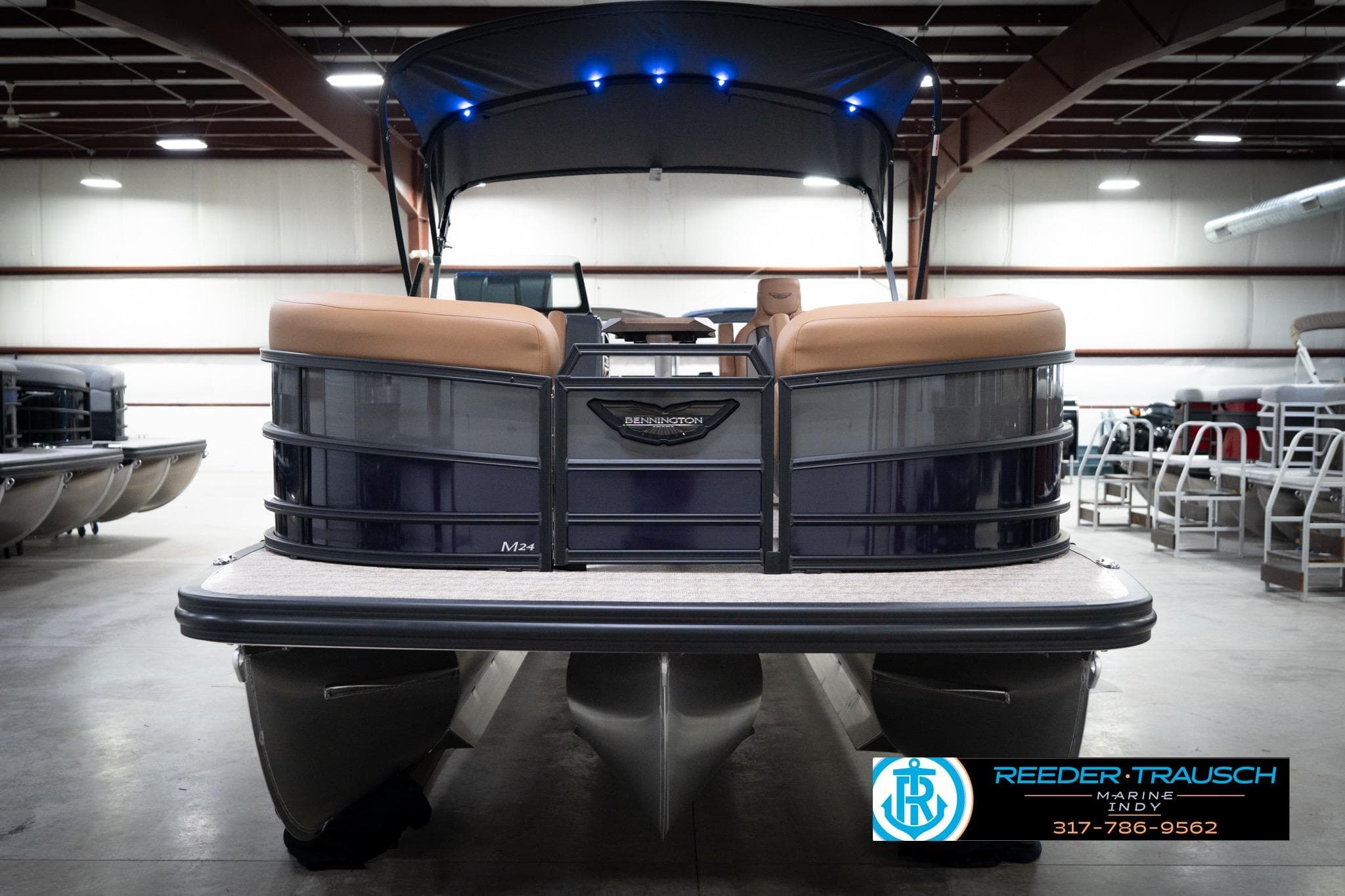 2026 Bennington 22 MFB pontoon boat in showroom with blue lights and tan seating.