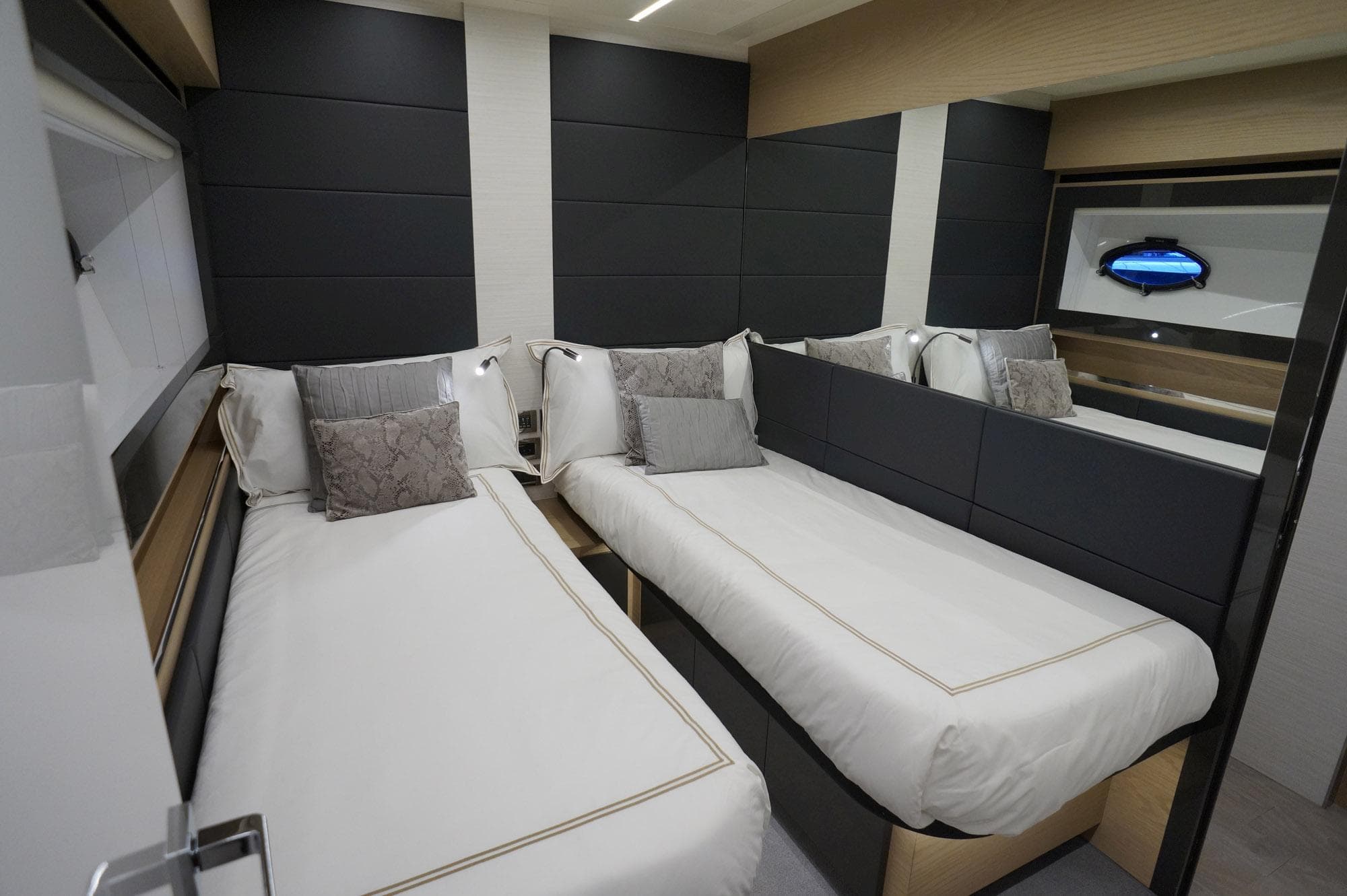 Luxurious twin bedroom in 2016 Pershing 70 yacht with modern decor and plush bedding.