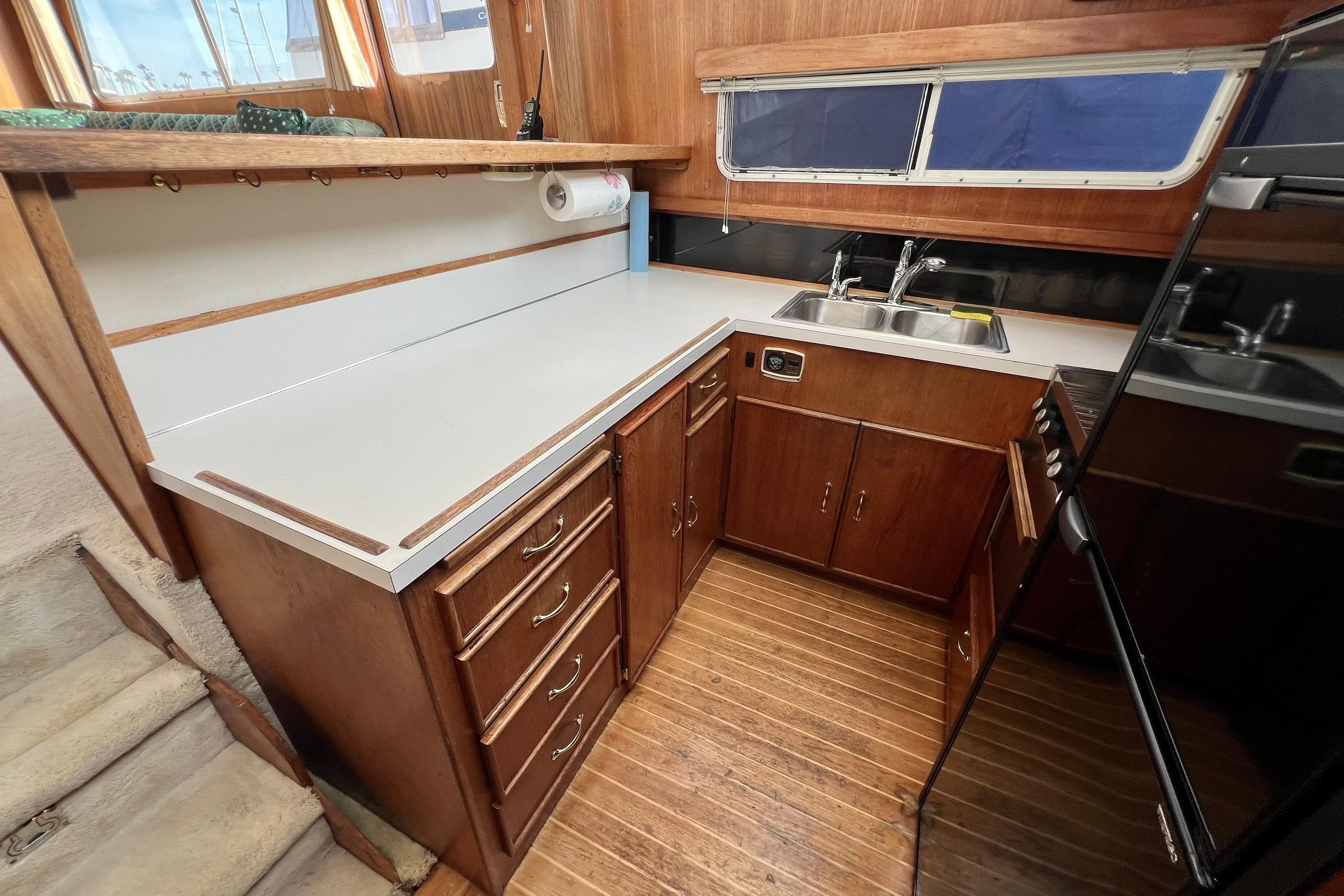 1985 Tollycraft 48 Cockpit Motor Yacht kitchen with wooden cabinets and dual sink.