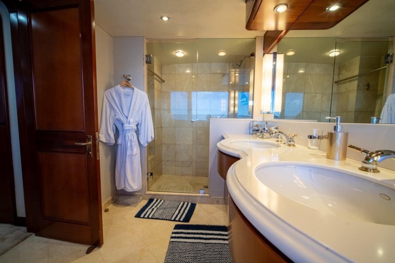 Luxurious yacht bathroom with double sinks, glass shower, and robe, Lloyds Ships Tri-Deck 1984.