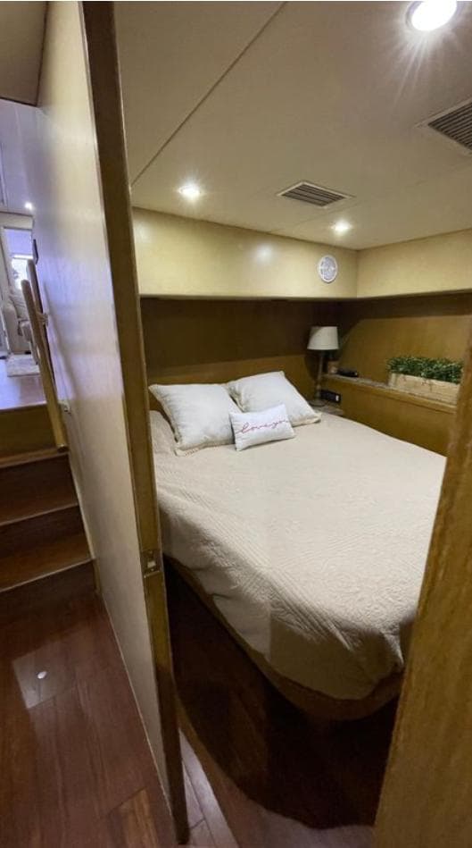 1995 Bertram Convertible yacht bedroom with cozy bed, wooden interior, and soft lighting.