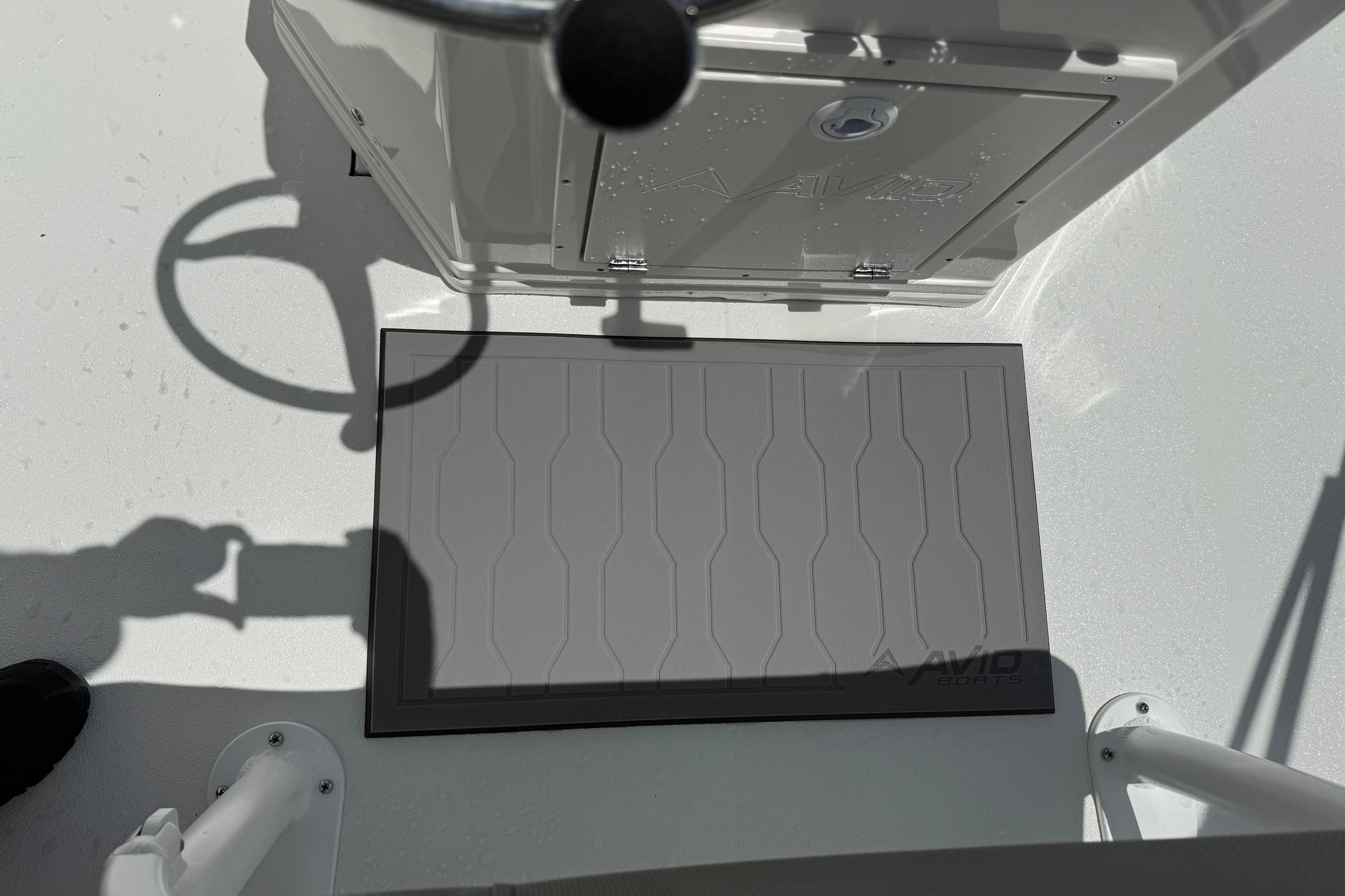 Avid 21 Mag 2026 boat deck with steering wheel and storage compartment.
