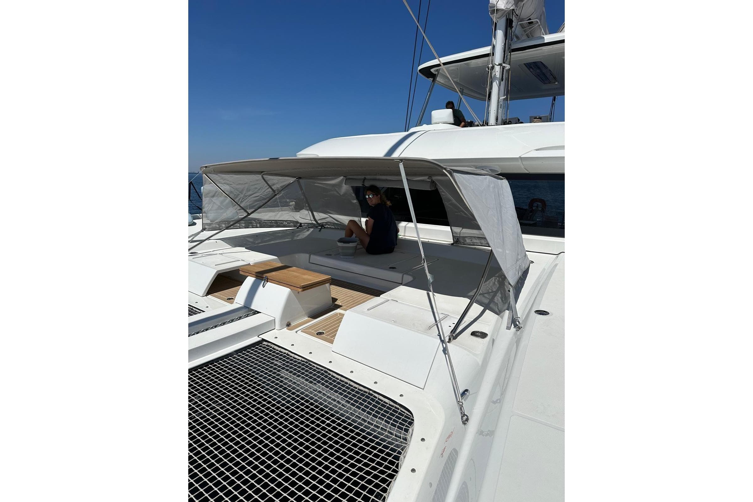 2023 Lagoon 55 yacht with shaded seating area on deck, under clear blue sky.