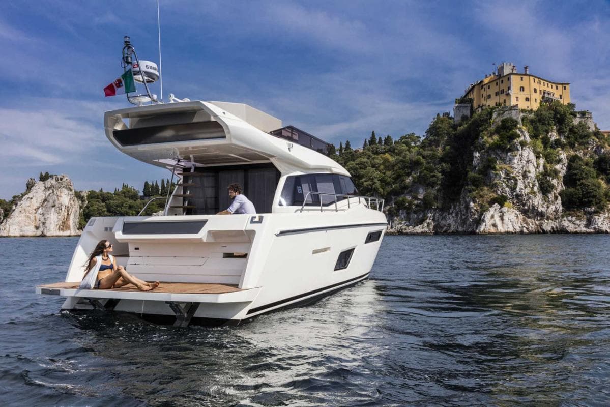 2017 Ferretti Yachts 450 cruising near scenic cliffs and historic building.
