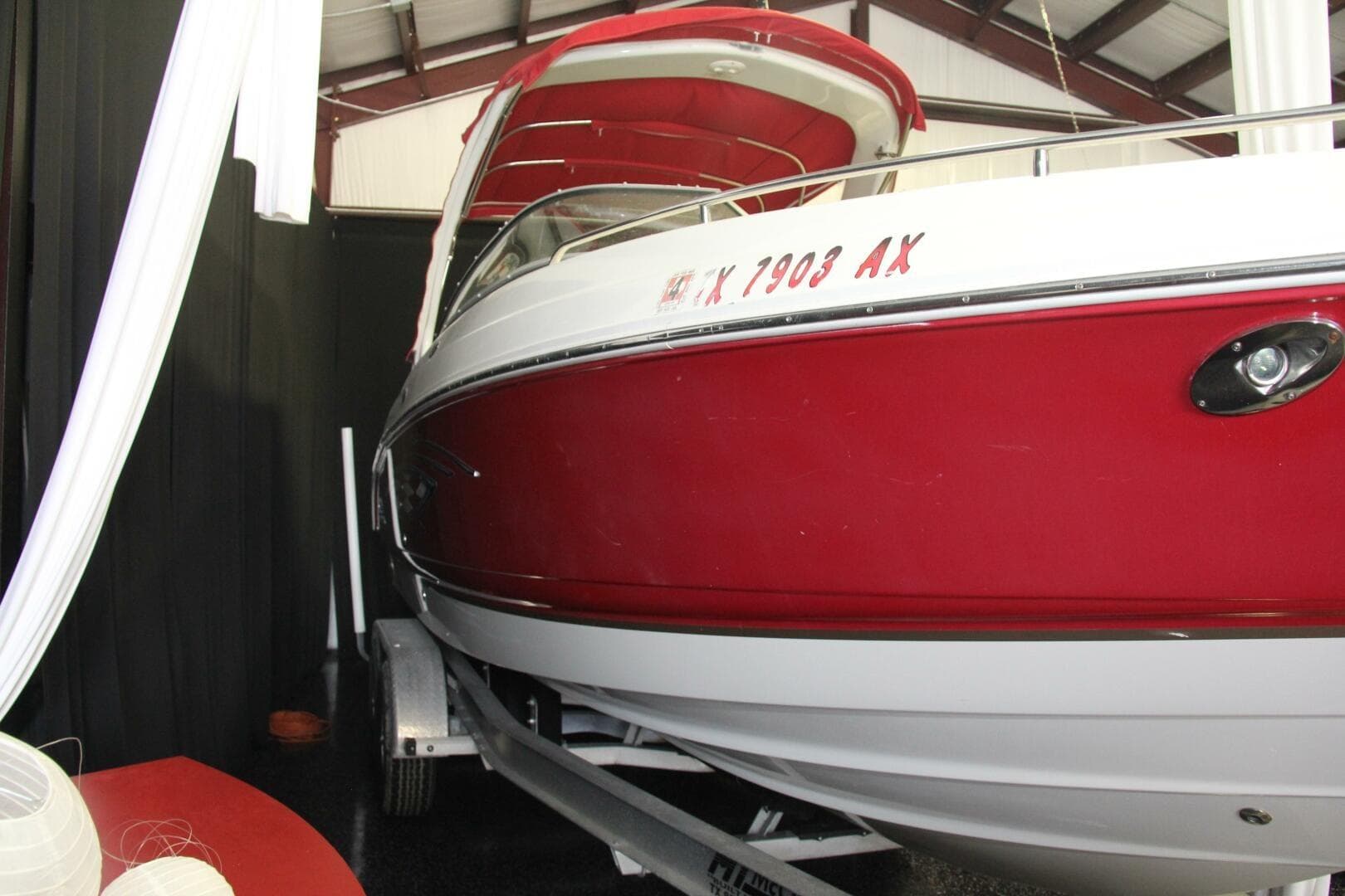 2006 Chaparral 256 SSi boat in red and white, displayed indoors on a trailer.