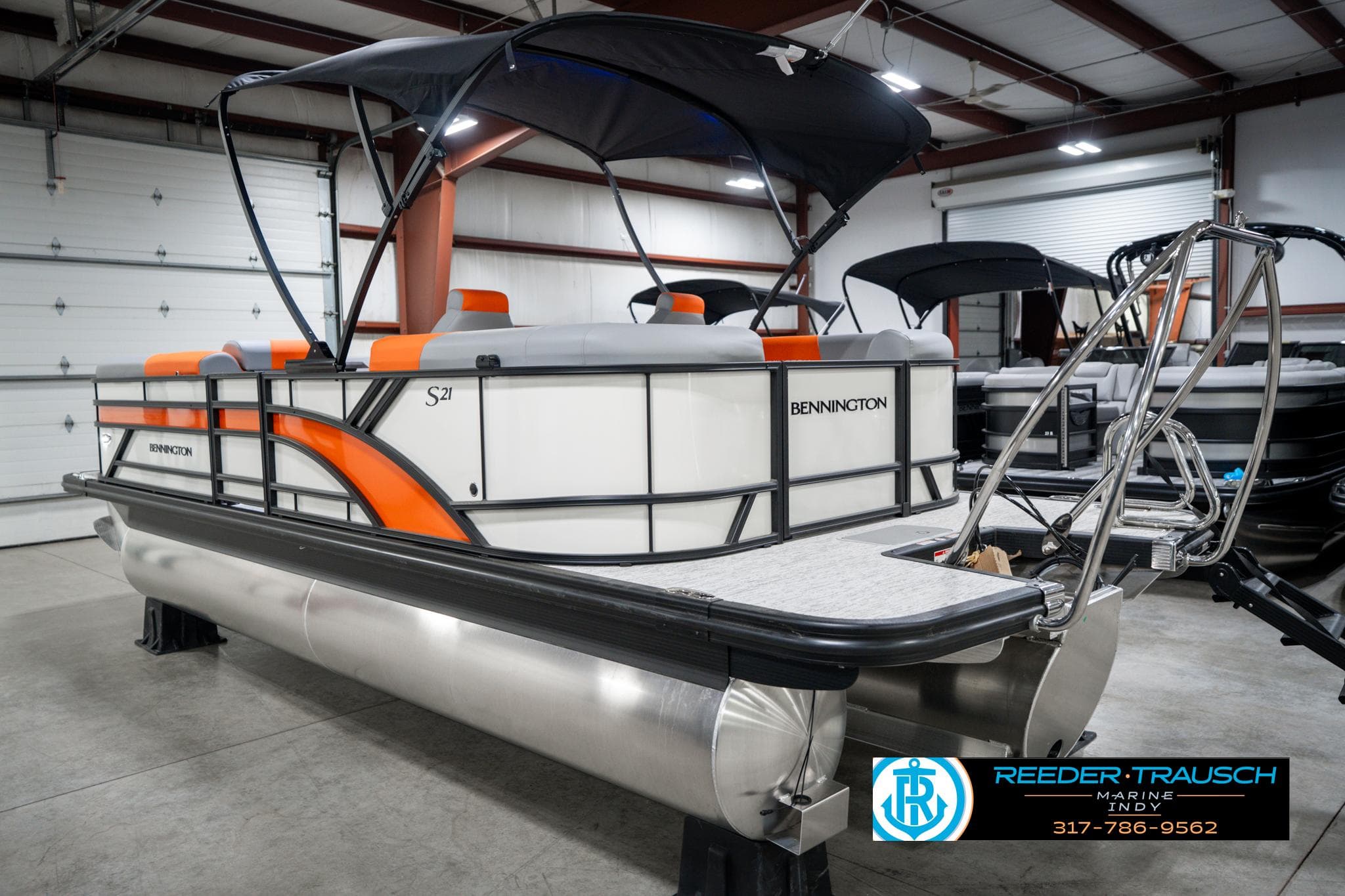 2025 Bennington 21 SSR pontoon boat with orange accents in a showroom.