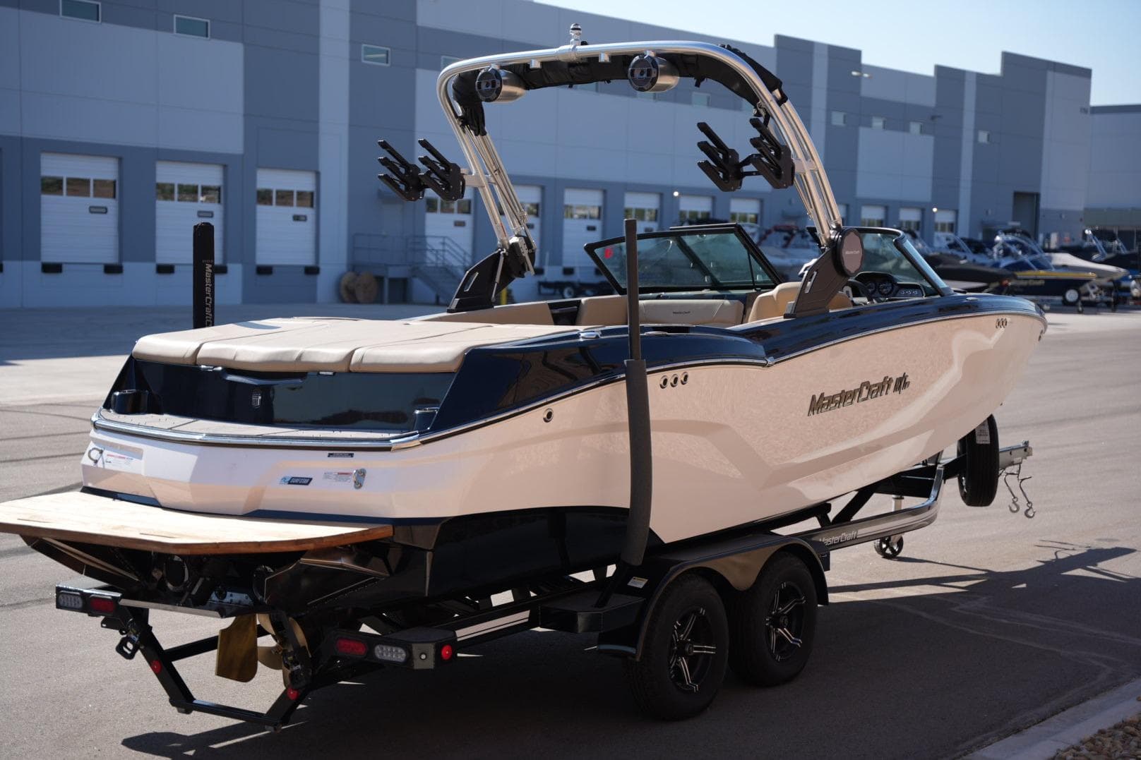 2023 MasterCraft NXT24 boat on trailer, parked outside industrial building.