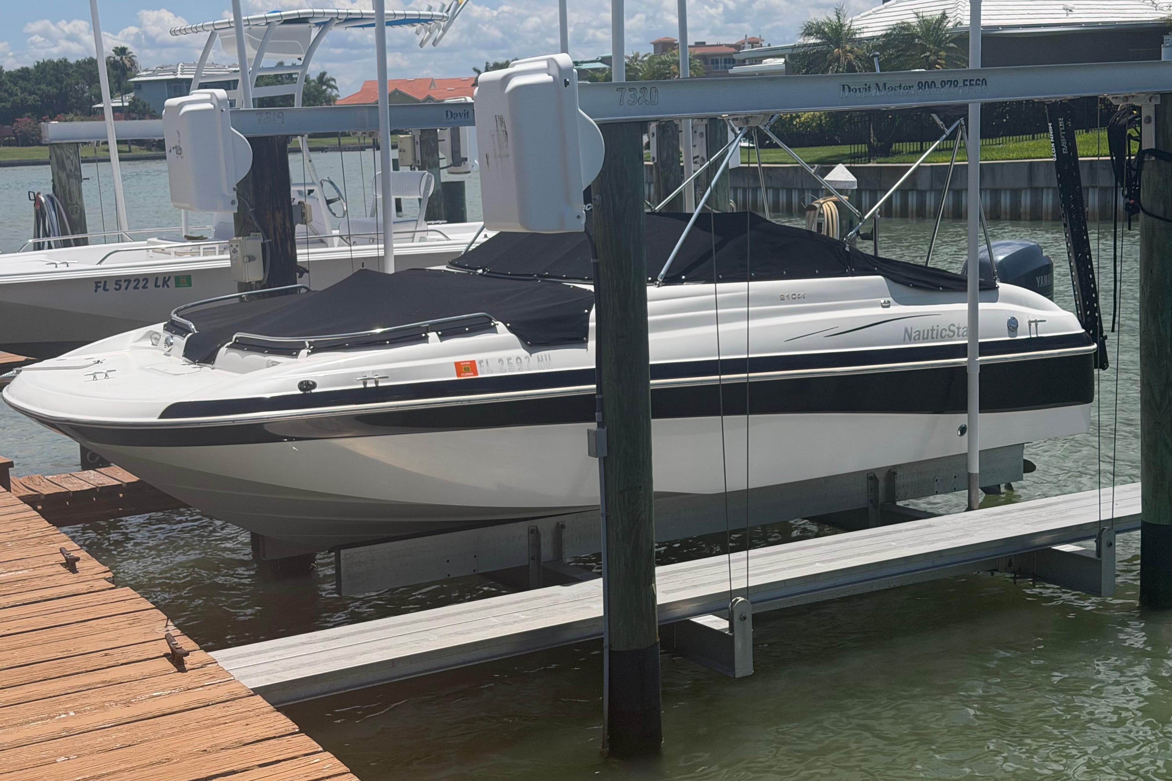 2008 NauticStar 210 DC Sport Deck boat docked on lift, covered and ready for use.