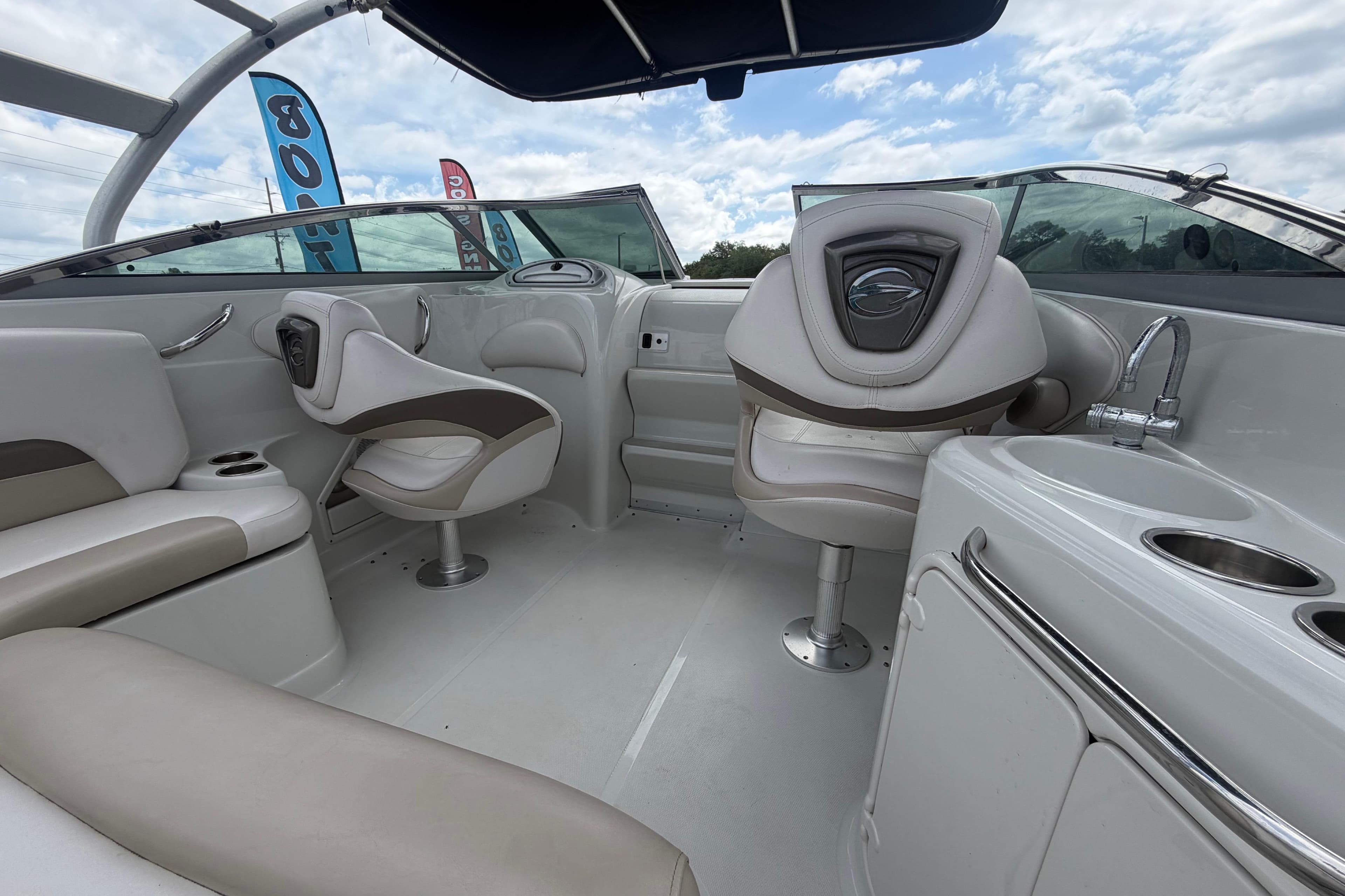 2012 Crownline 236 SC boat interior with seating and sink under a cloudy sky.