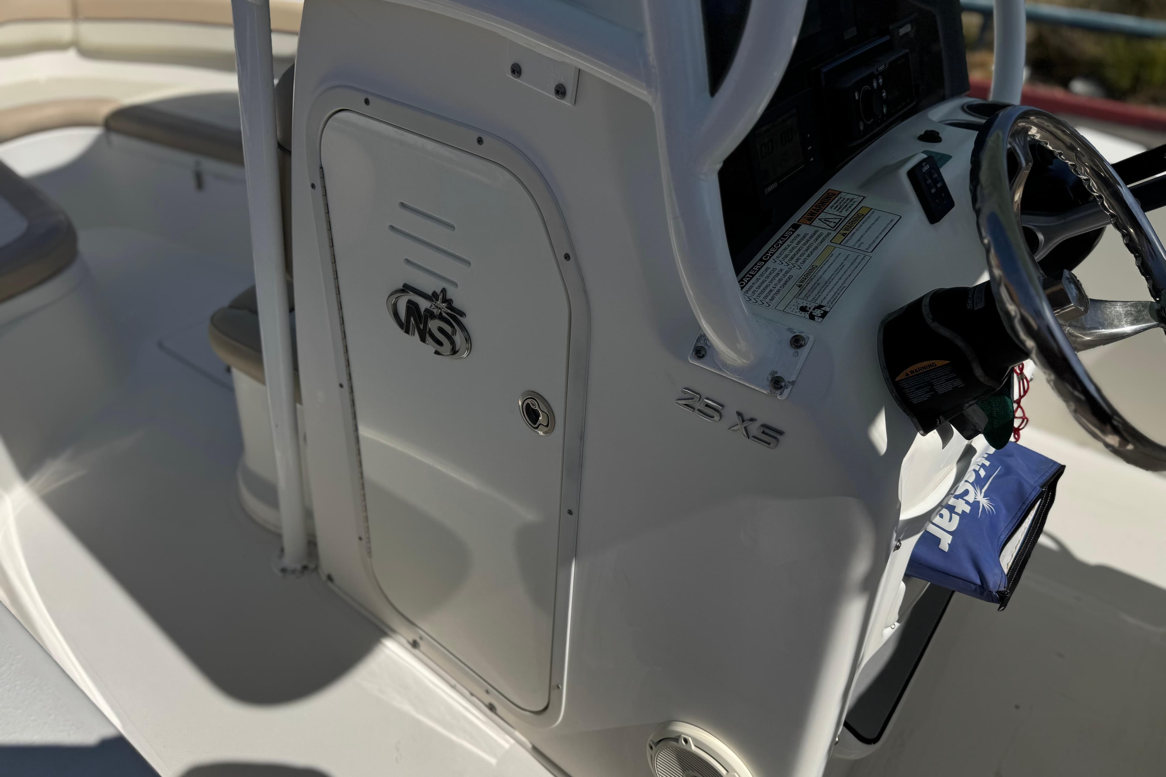 2018 NauticStar 25 XS boat console with steering wheel and storage compartment.