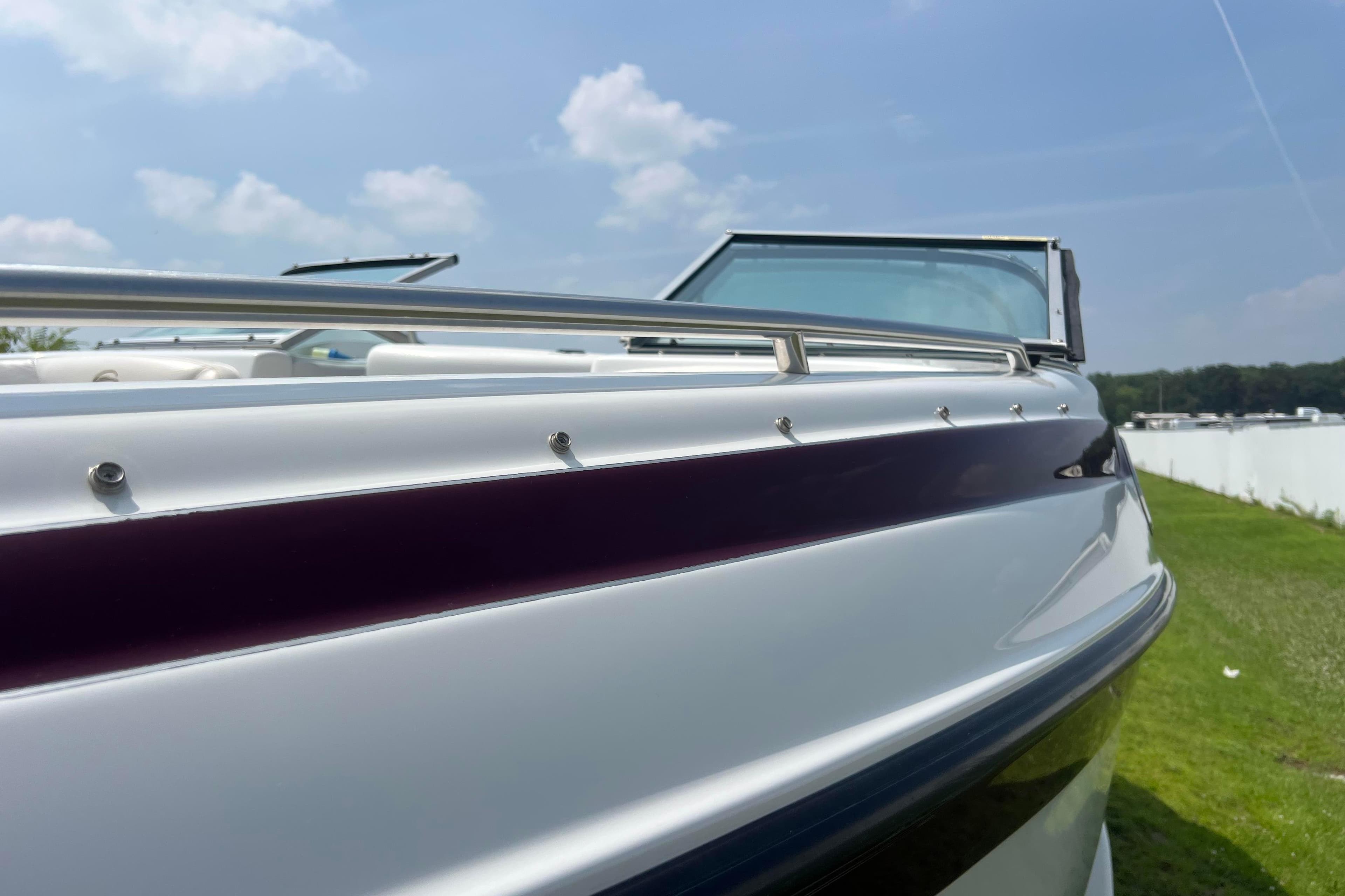 2003 Crownline 230 BR boat, sleek design, sunny day, grassy background.