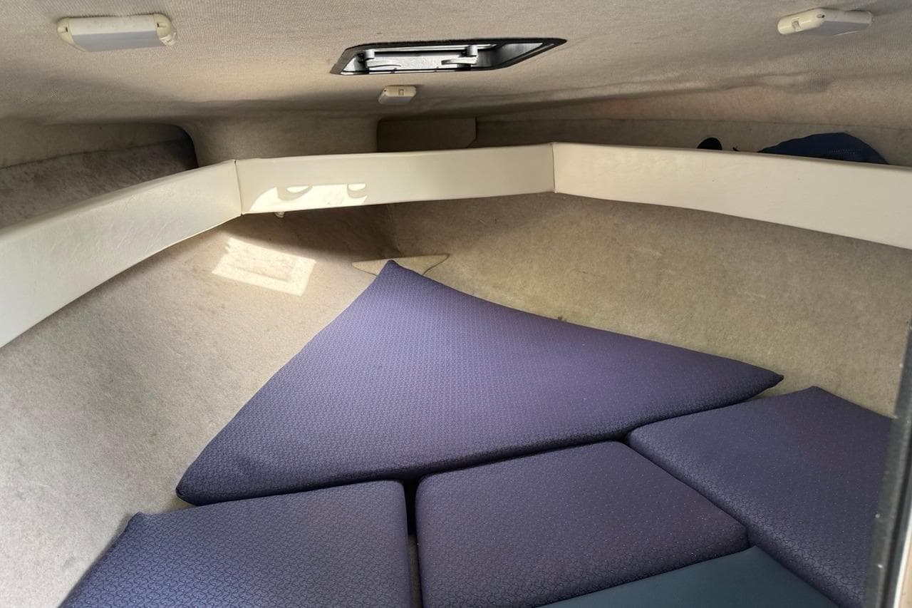 2005 Bayliner 210 Discovery cabin interior with blue cushions and overhead hatch.
