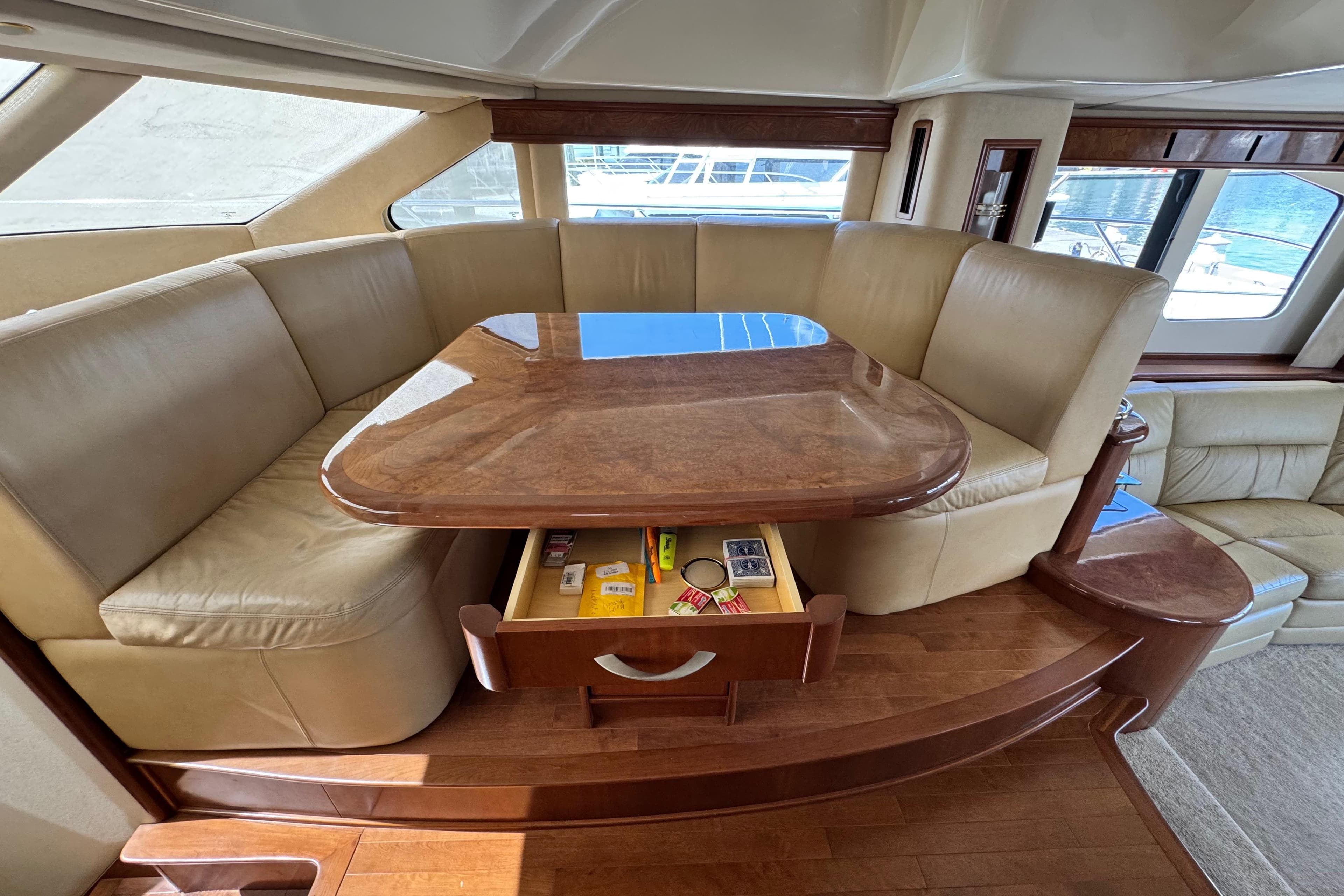 Luxurious seating area on 2009 Ovation 52 yacht with wooden table and storage drawer.