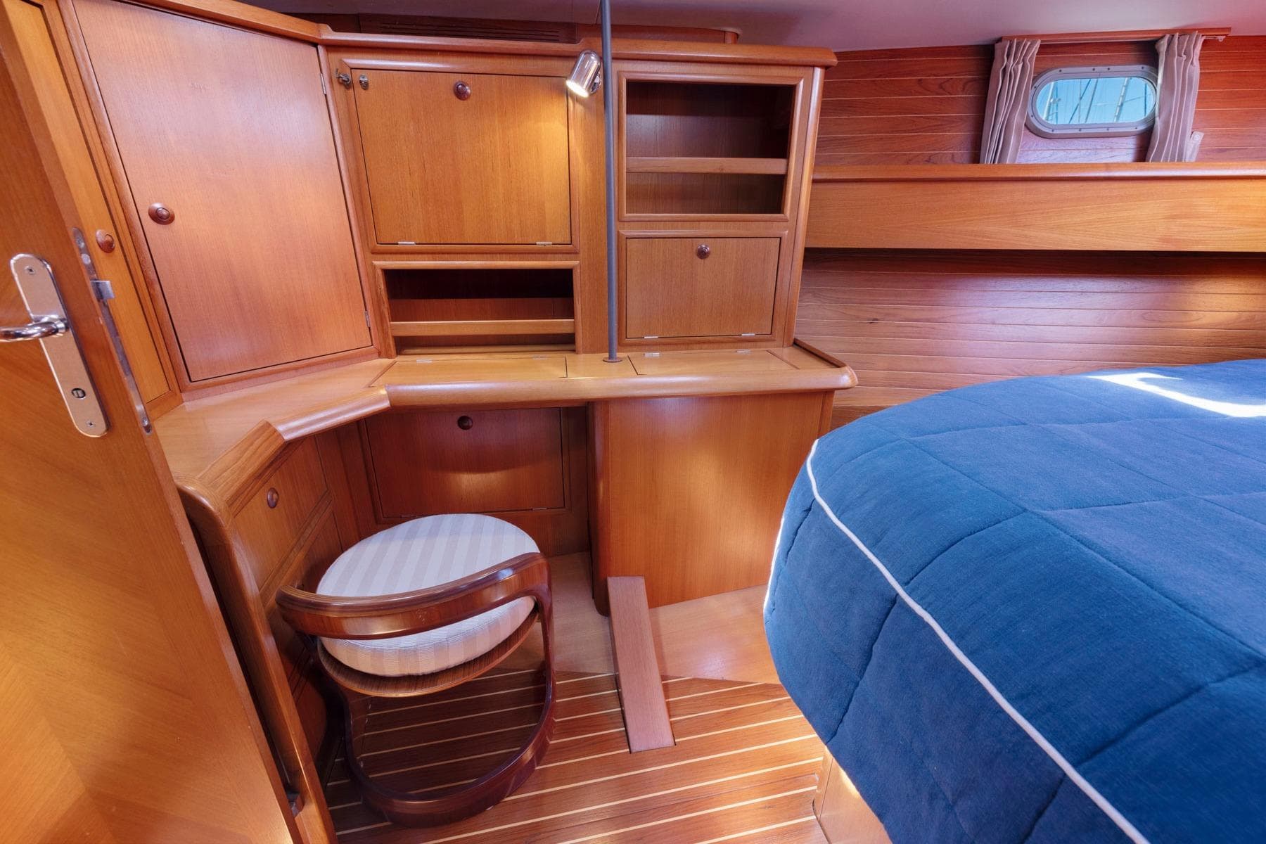 Cozy cabin interior of 2001 Jeanneau Sun Odyssey 52.2 with wooden furnishings and blue bedding.