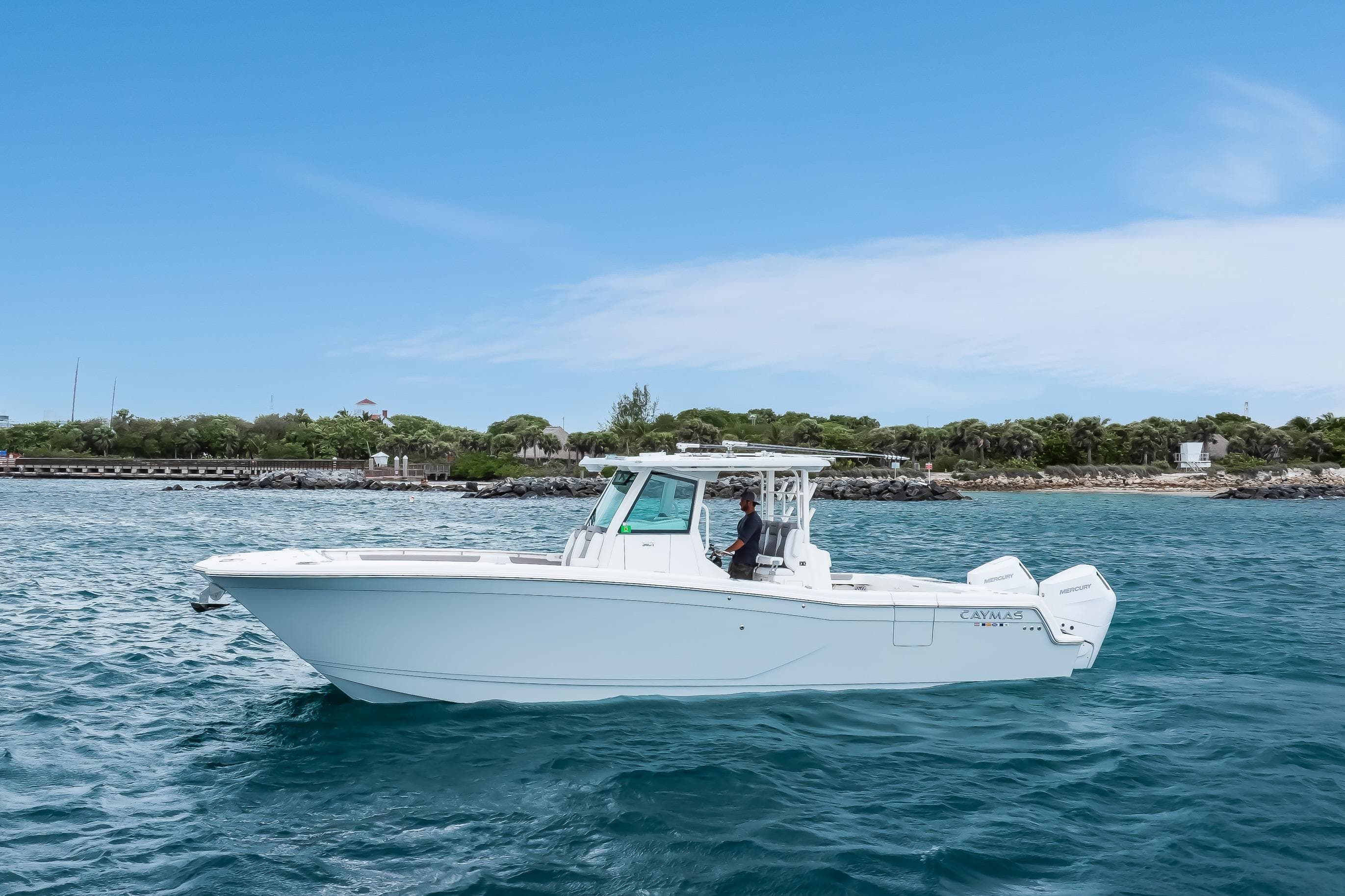 2024 Caymas 341 CC boat cruising on blue ocean near lush coastline.