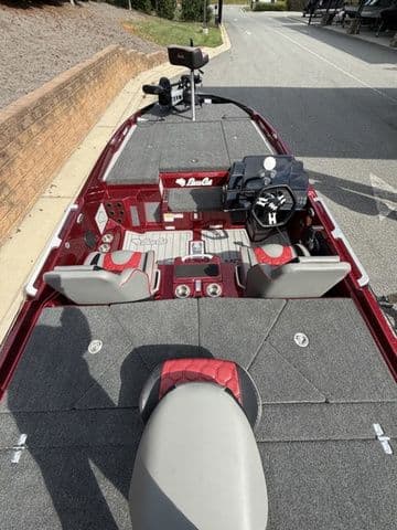 2026 Bass Cat Lynx STS boat interior with red and gray seating, steering console, and fishing equipment.
