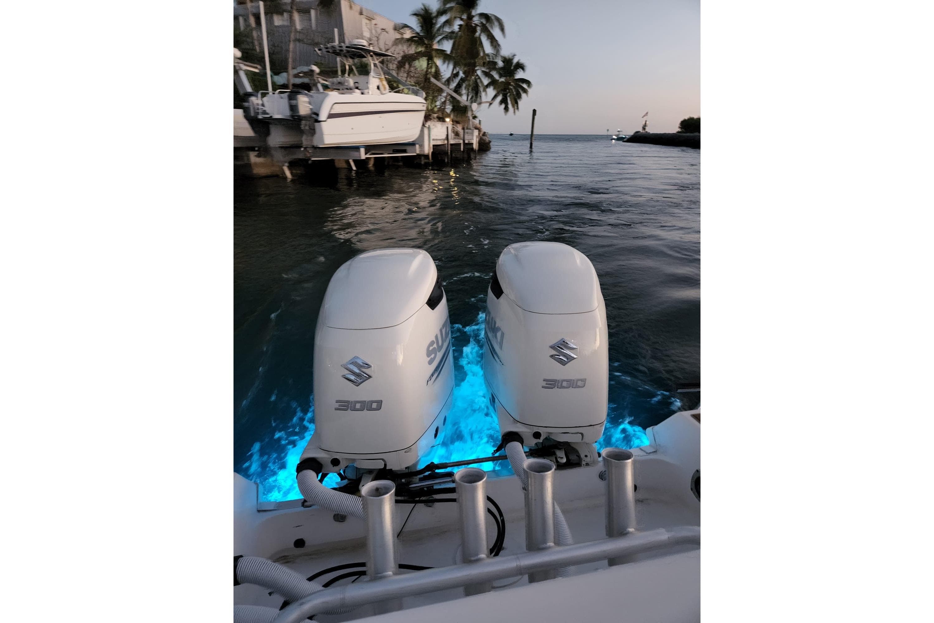 2004 Wellcraft 290 Coastal boat with dual Suzuki 300 engines, illuminated by blue underwater lights.