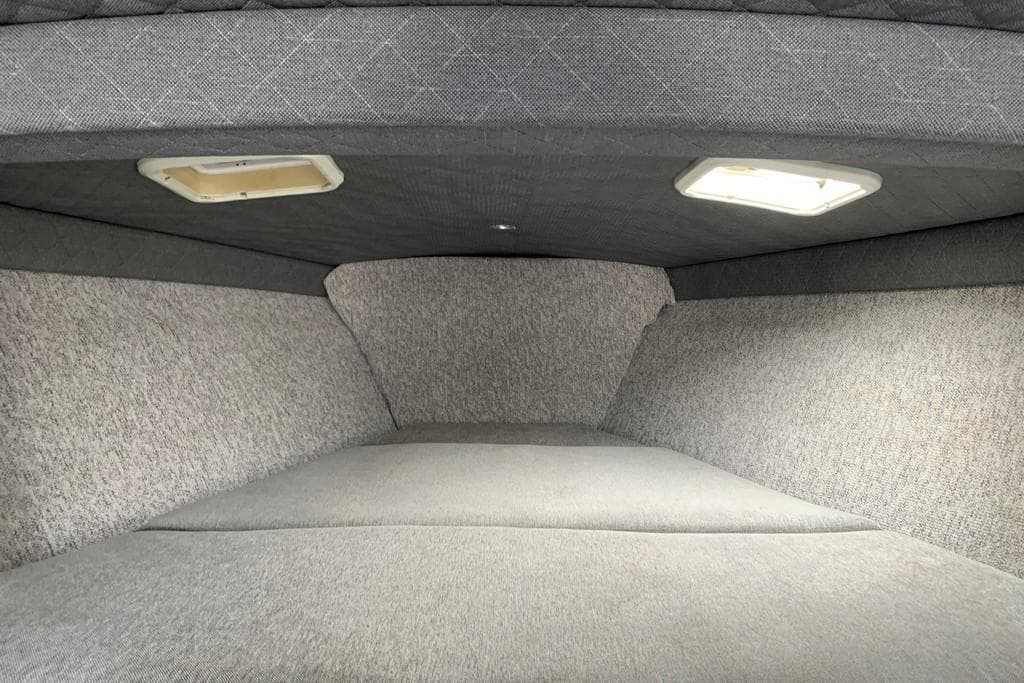 Interior cabin of 1999 Formula 382 FASTech boat with gray upholstery and overhead lighting.